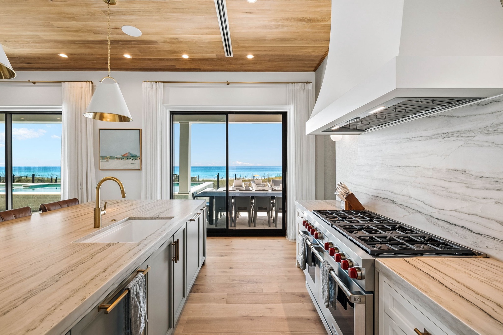 Prepare meals in this stunning kitchen where warm wood and elegant marble frame endless ocean views through expansive glass doors.