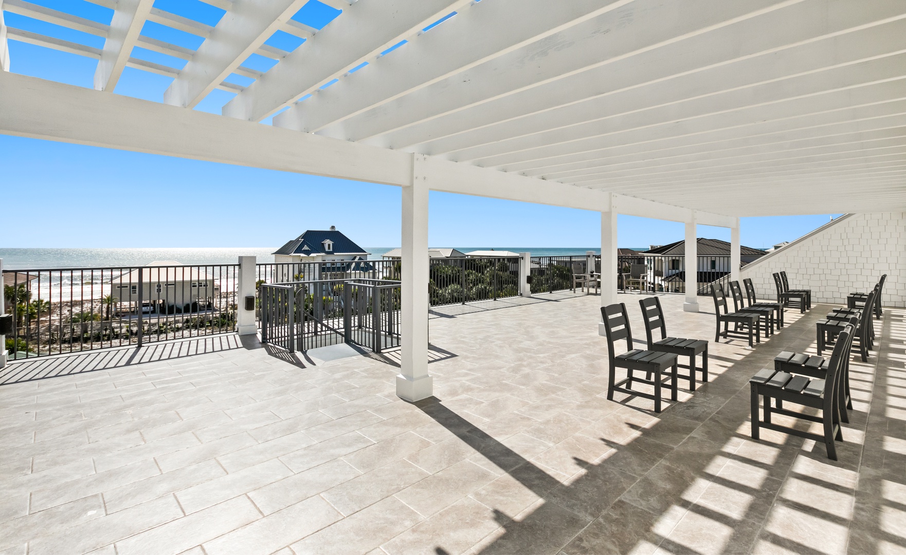 A spacious rooftop terrace with a pergola shelters rows of rocking chairs, creating the perfect spot for you to relax and enjoy the coastal views.