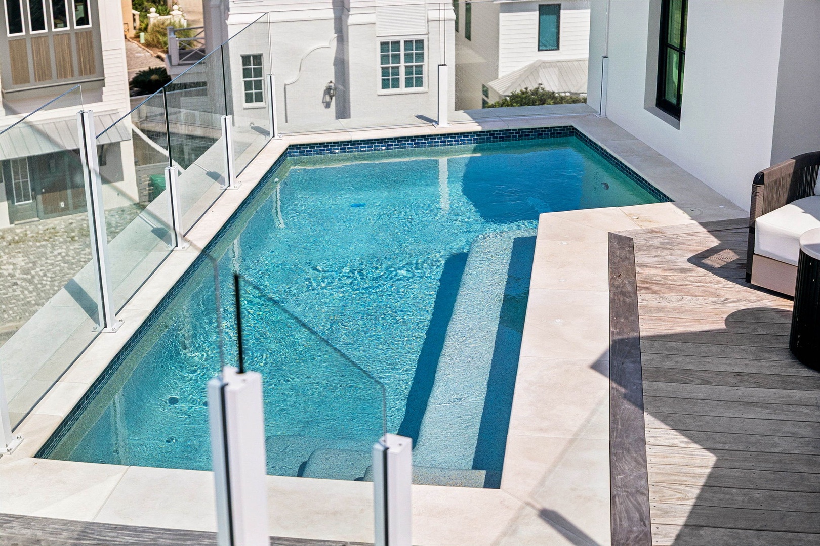 Modern private pool with glass safety fencing, tiled trim, and sun-drenched pool deck—perfect for relaxing sunny days and refreshing swims.