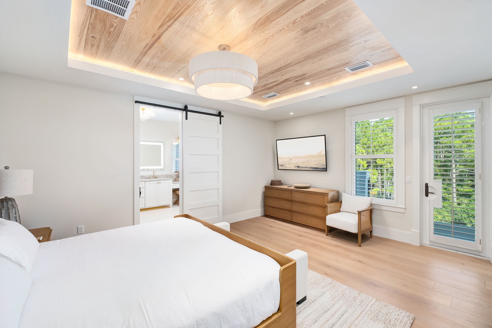 Drift off under a glowing wood-paneled ceiling in your spacious bedroom, where a sliding barn door leads to the ensuite and bright windows open to the outdoor balcony. A perfect retreat to unwind and recharge.