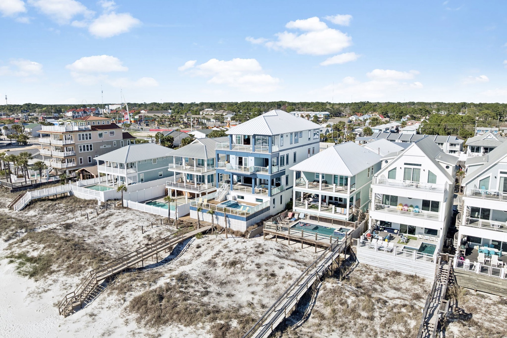 Aerial view showcasing beachfront vacation homes with pools and private beach access along pristine white sand dunes.