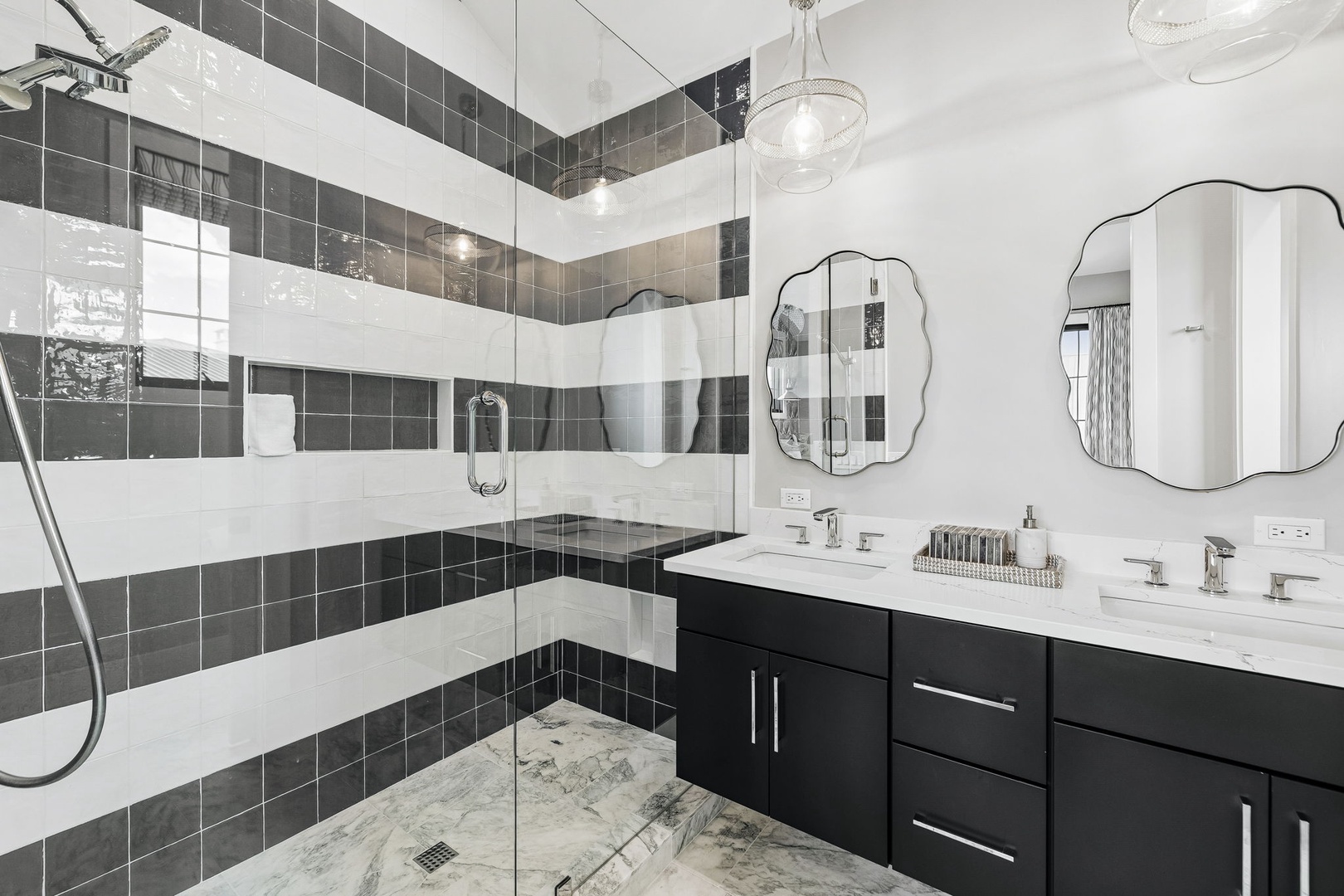 Step into your spa-like bathroom featuring bold striped tilework, dual vanities with elegant mirrors, and a spacious walk-in shower that invites you to unwind in style.