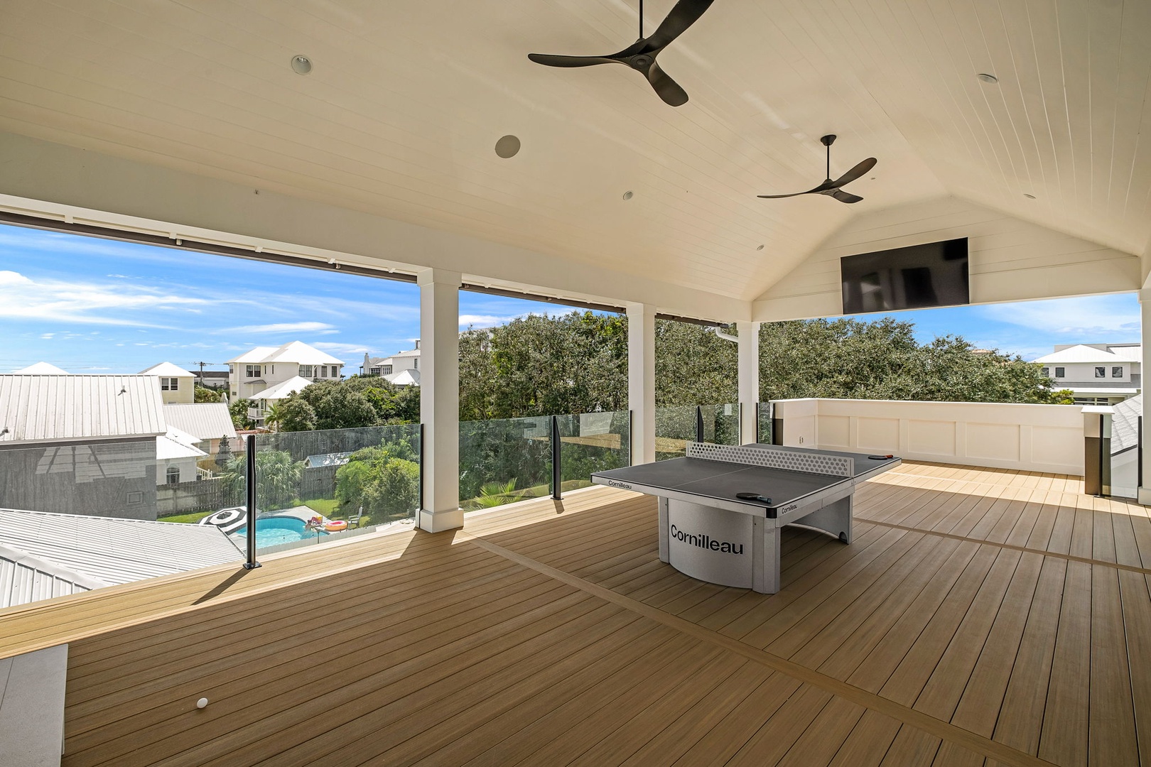 A covered game area with expansive glass doors opens to natural light and tree-lined views—perfect for relaxing, playing, or gathering.