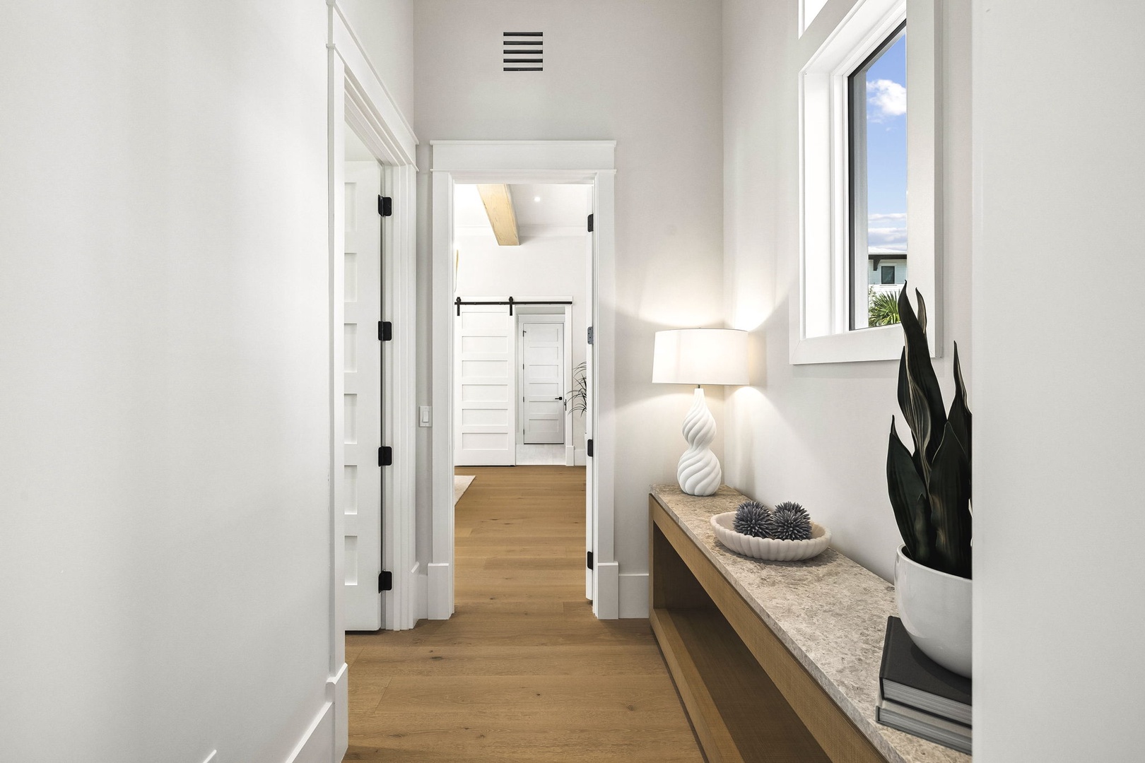 Bright hallway with warm hardwood floors and modern décor welcomes you, connecting you to the rest of your peaceful retreat.