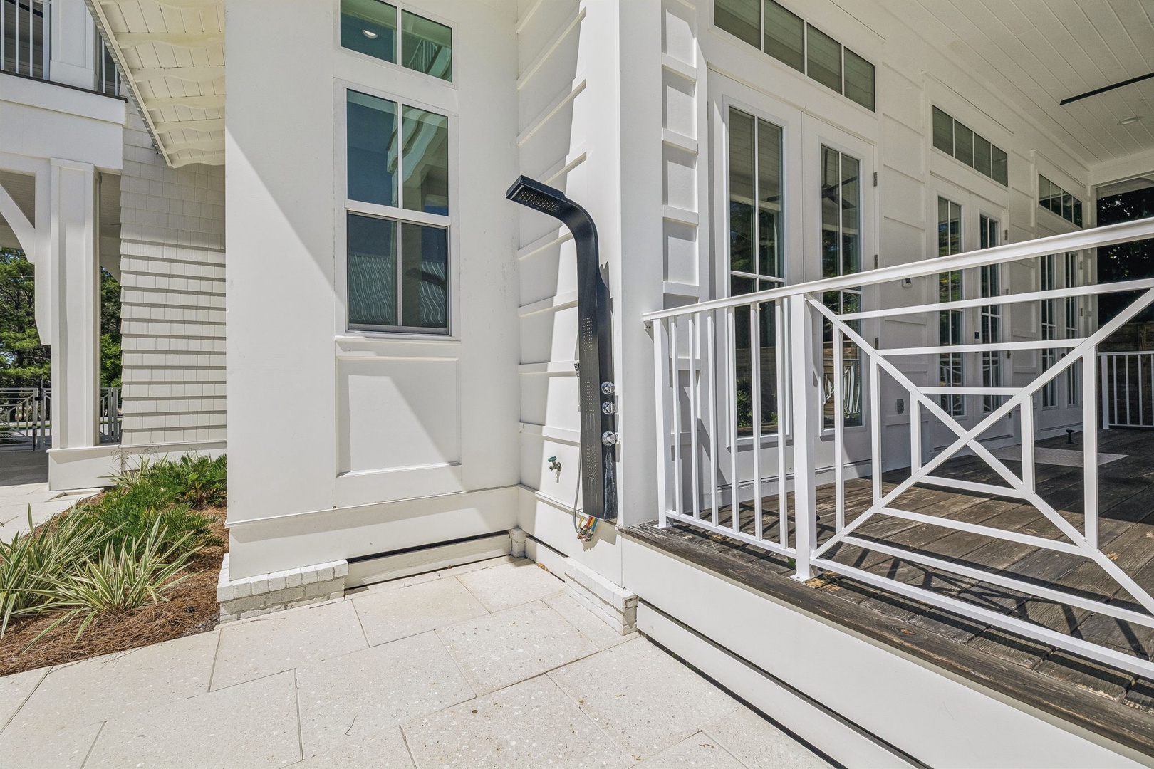 A charming outdoor shower awaits you on this sunny patio, perfect for rinsing off after a beach day or pool session. The crisp white architecture and decorative railings add a coastal touch to your private retreat.