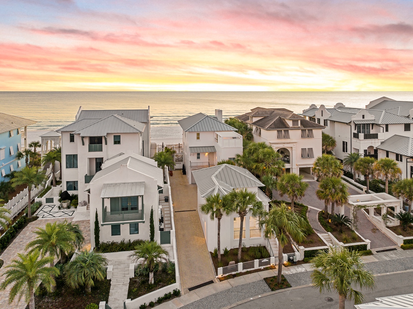 Stunning beachfront homes line the coast as golden sunset colors paint the evening sky over this exclusive neighborhood.