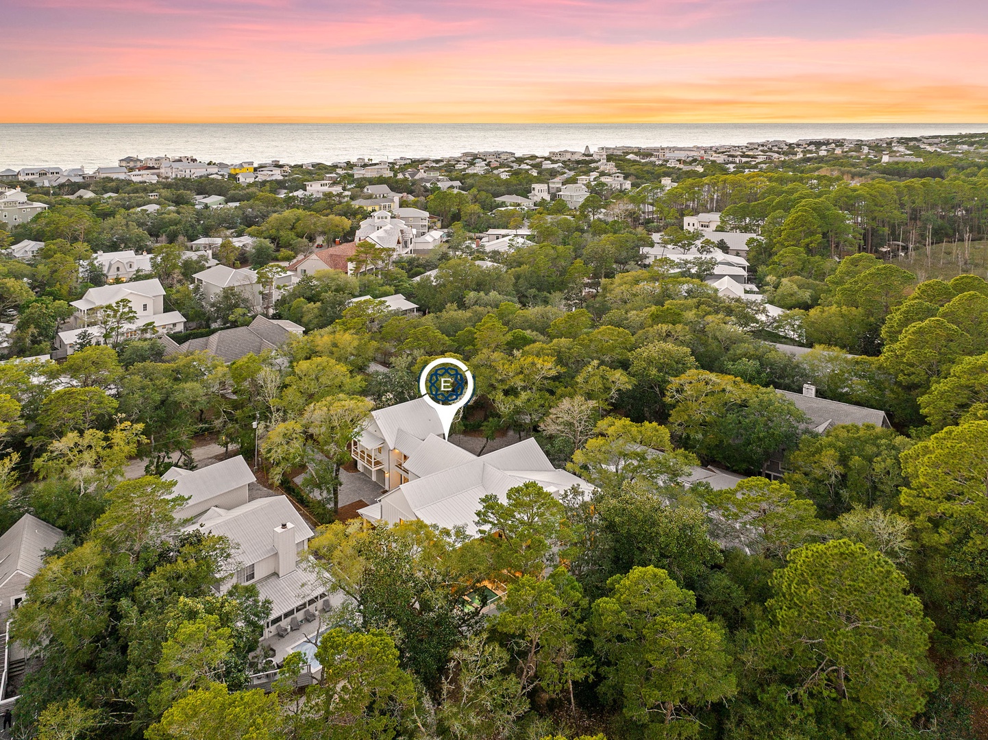 Aerial view of a coastal neighborhood with homes nestled among lush trees, just minutes from the pristine beach.