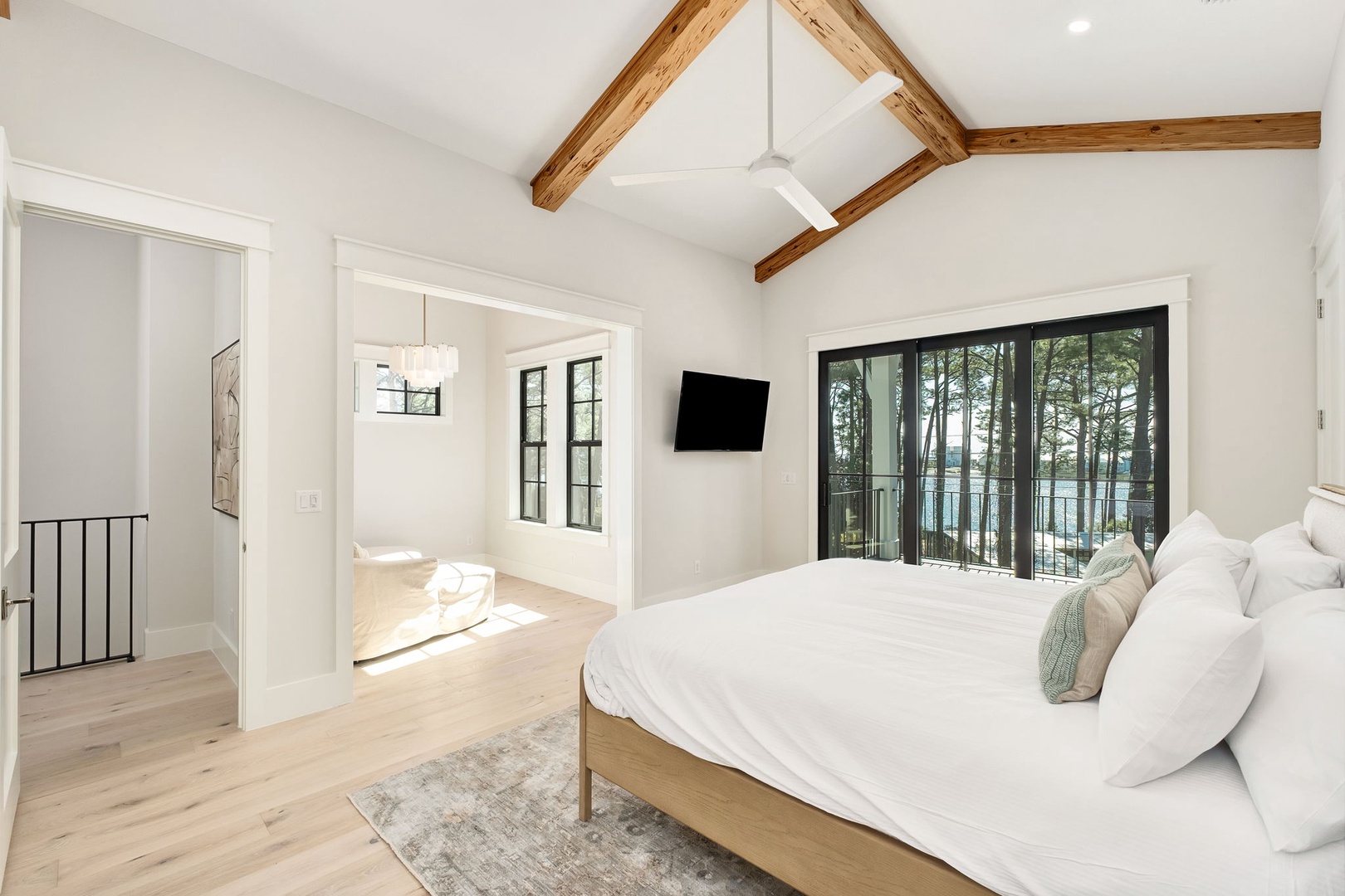 Wake up in this stunning bedroom with exposed beams and balcony doors opening to serene lake views—your perfect retreat.
