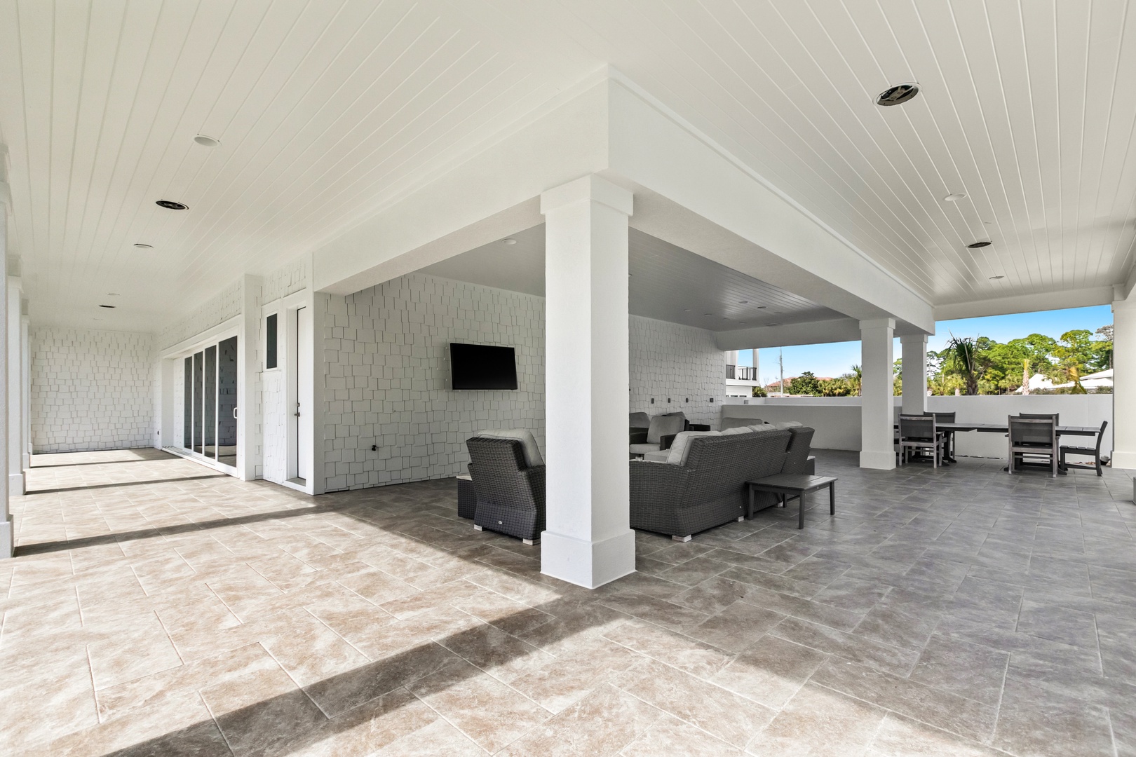 Relax in your expansive covered outdoor living area with comfortable seating, dining space, and a TV—perfect for enjoying Florida's sunshine and warm breezes while lounging with friends and family.