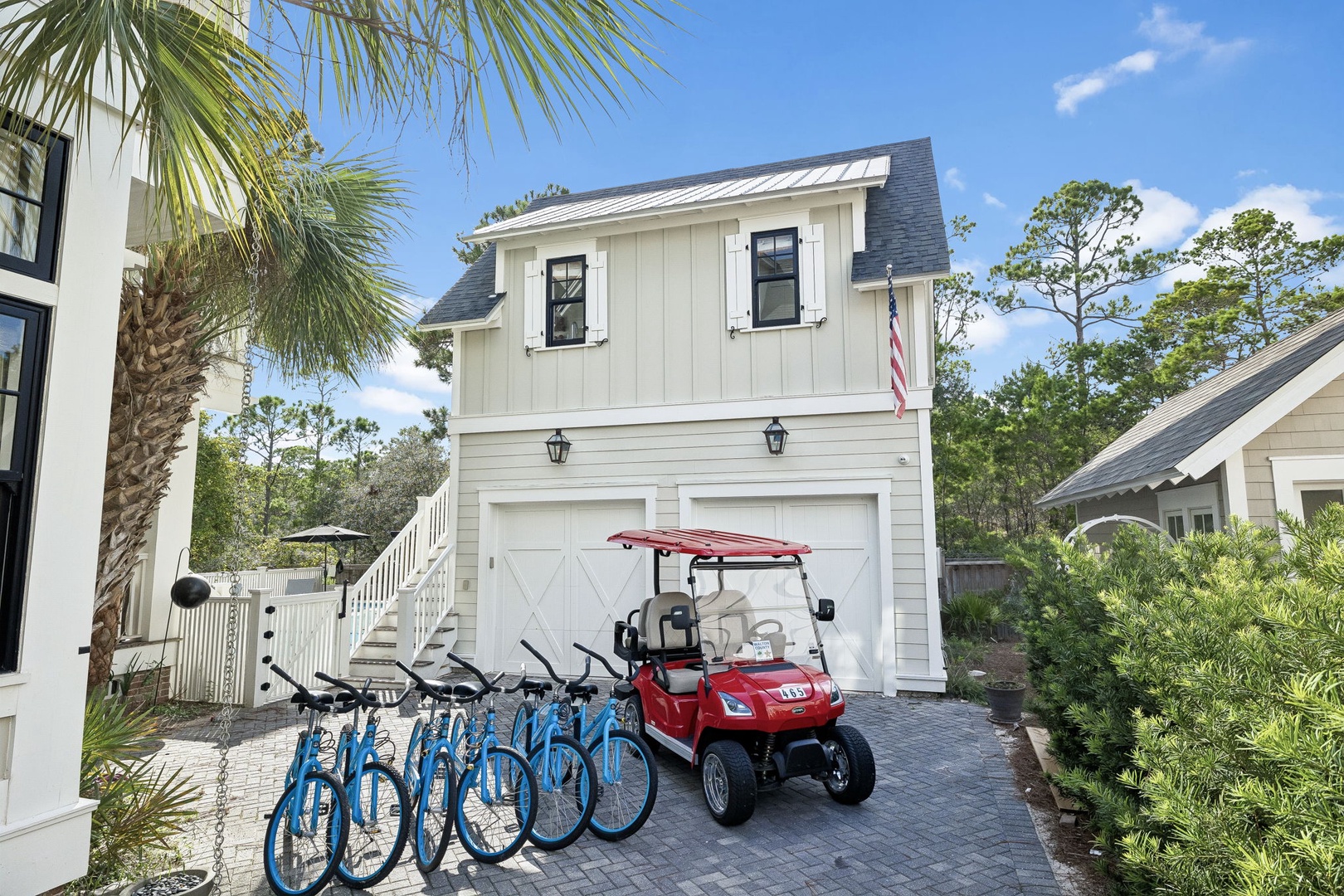 The charming white building with modern farmhouse appeal sits nestled among lush greenery and palms, offering bicycles and a golf cart for your local adventures.