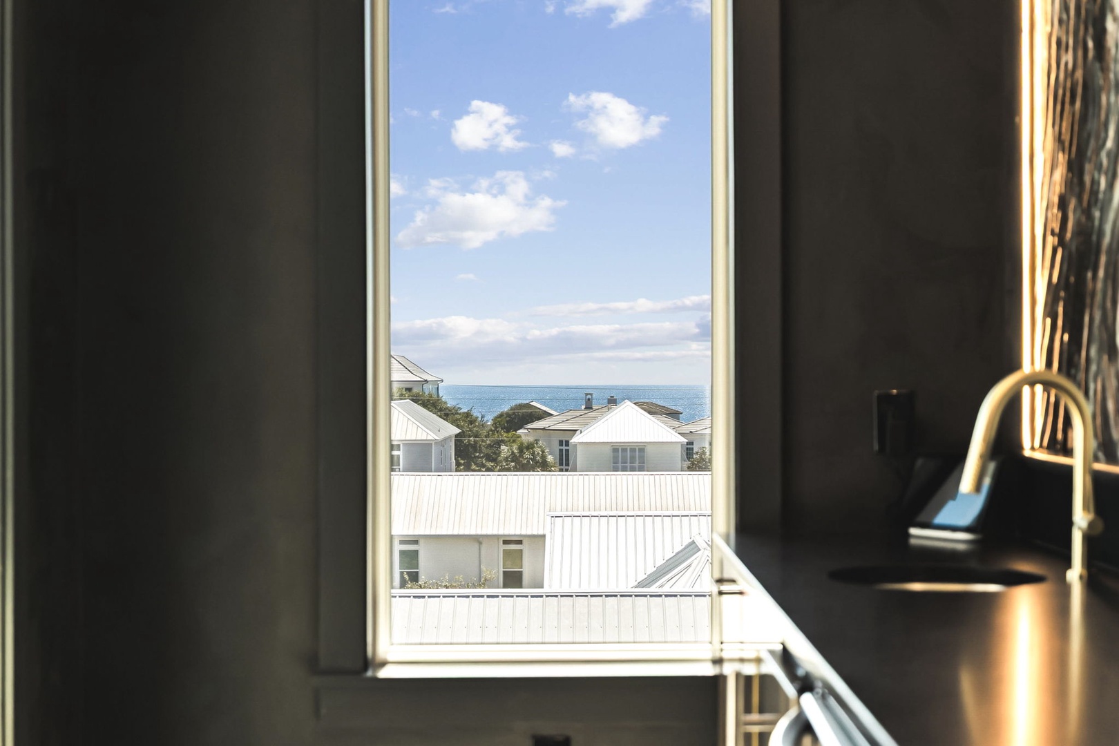 Step into your bright, modern kitchen and catch a glimpse of the sparkling ocean on the horizon through the window—your coastal escape awaits.