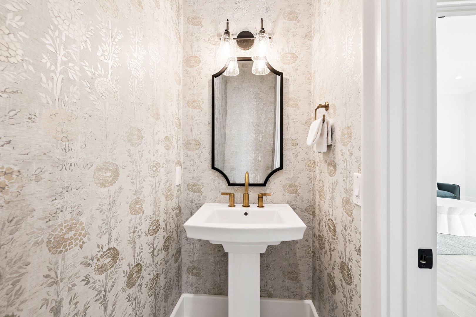 Freshen up in this elegant powder room with chic botanical wallpaper and brass fixtures creating a sophisticated retreat.