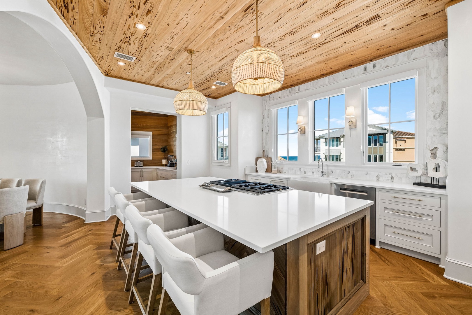Gather with loved ones in this stunning kitchen with a spacious island, modern appliances, and warm wood accents beneath a beautiful natural wood ceiling. Sunlight pours through the windows as you cook and create.