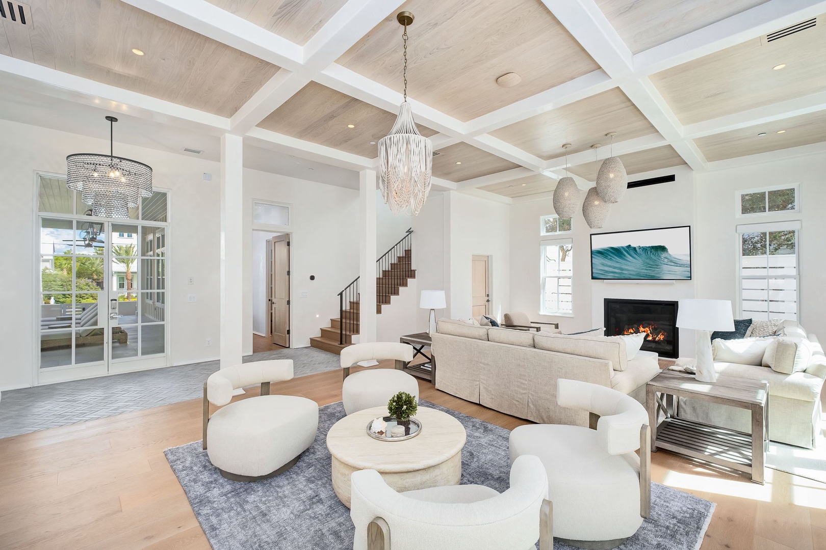 Sink into plush seating beneath soaring coffered ceilings while natural light pours through tall windows. Your coastal escape features a cozy fireplace and an open, airy design perfect for gathering with loved ones.