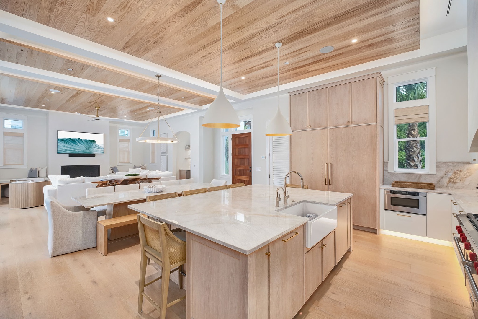 Step into an airy open-plan space where soaring wood-planked ceilings meet modern comfort. Your gourmet kitchen flows seamlessly into a bright dining and living area, perfect for gathering and unwinding together.