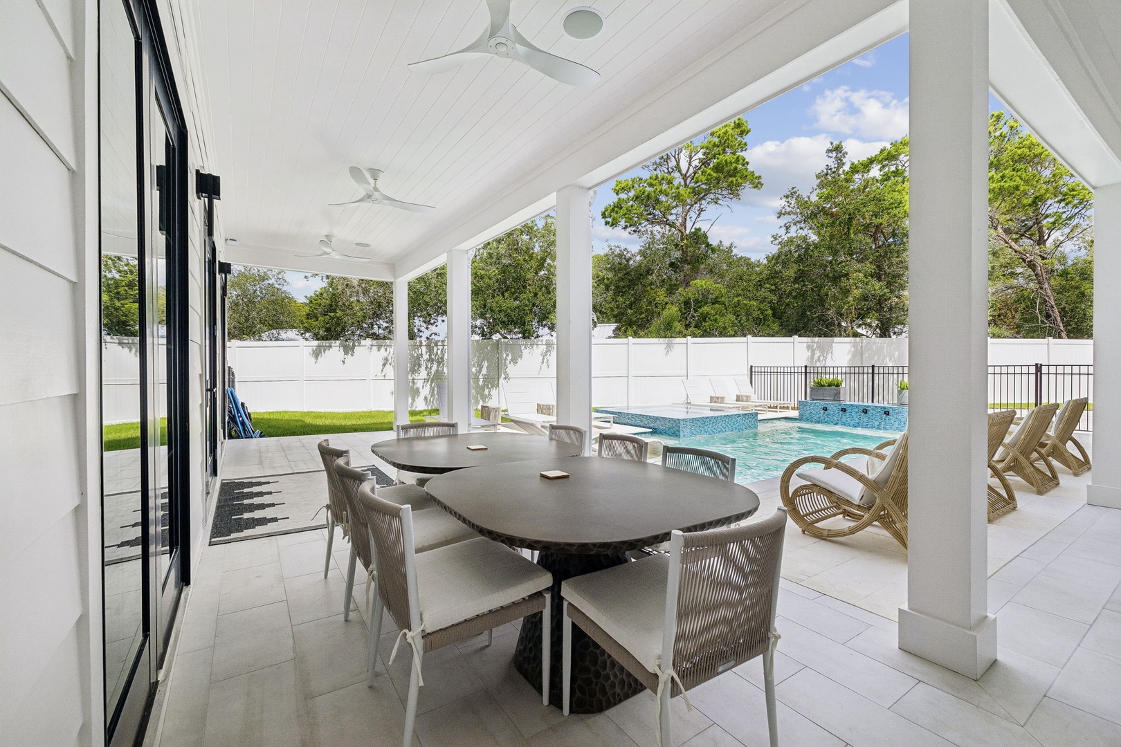 Dine al fresco under the breezy covered patio, where your private pool sparkles in the sunshine and lush greenery frames a serene escape beyond the fence.