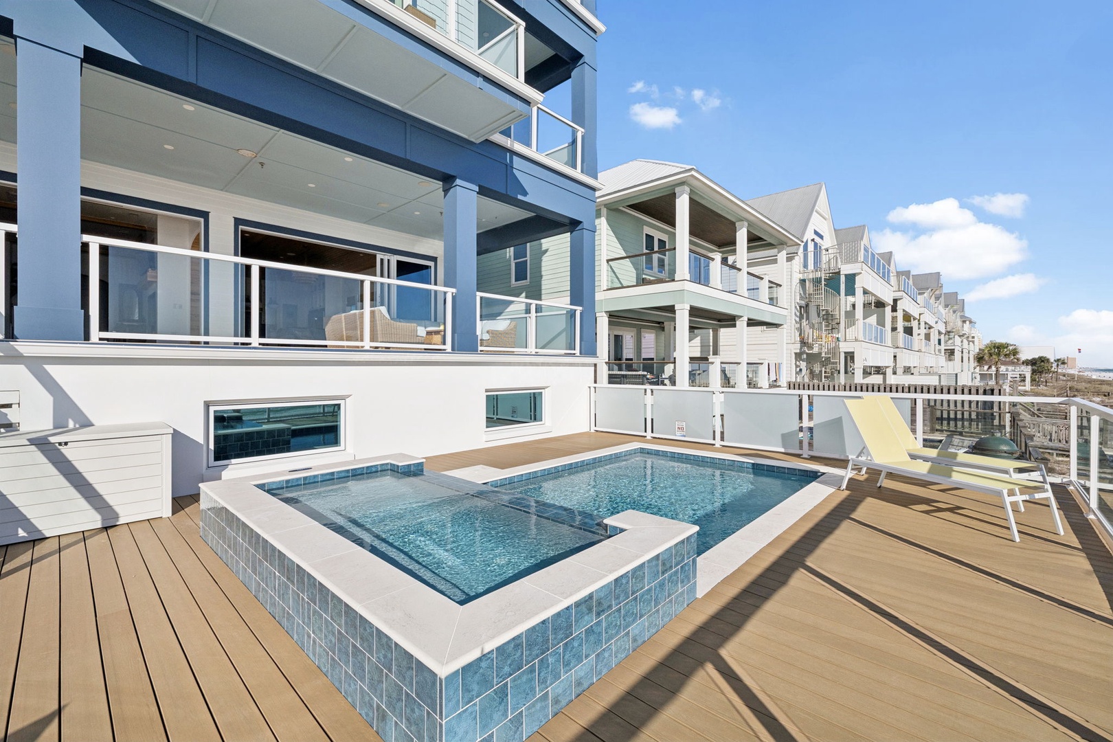 Modern beachfront property featuring a private hot tub on an expansive wooden deck with contemporary coastal architecture.