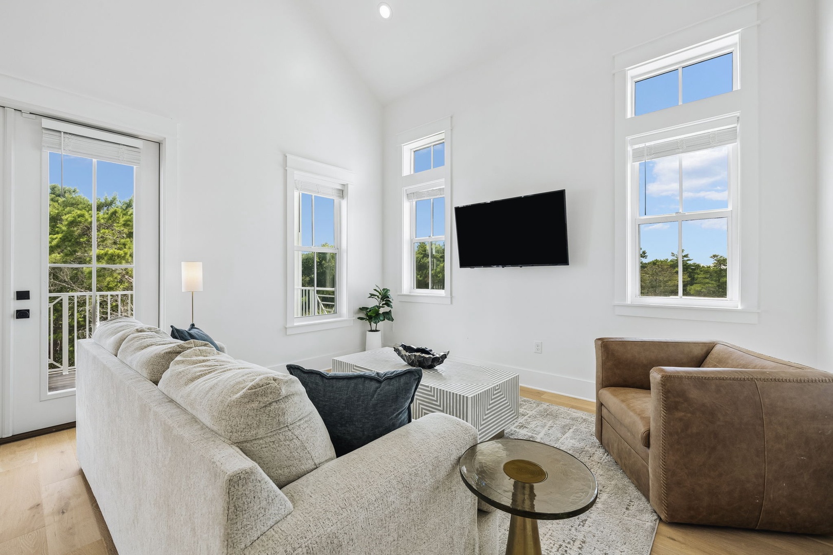 Sink into plush seating and enjoy your favorite shows in this bright, airy living room—natural light pours through tall windows framing leafy views, perfect for unwinding after a day of exploring.
