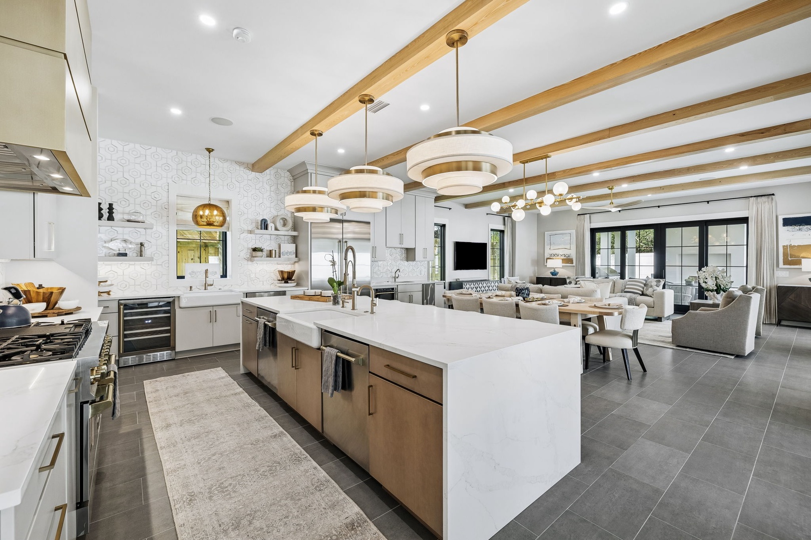 Chef's kitchen with warm wood beams and pendant lighting flows seamlessly into the living area, featuring a spacious island perfect for entertaining and making vacation memories.