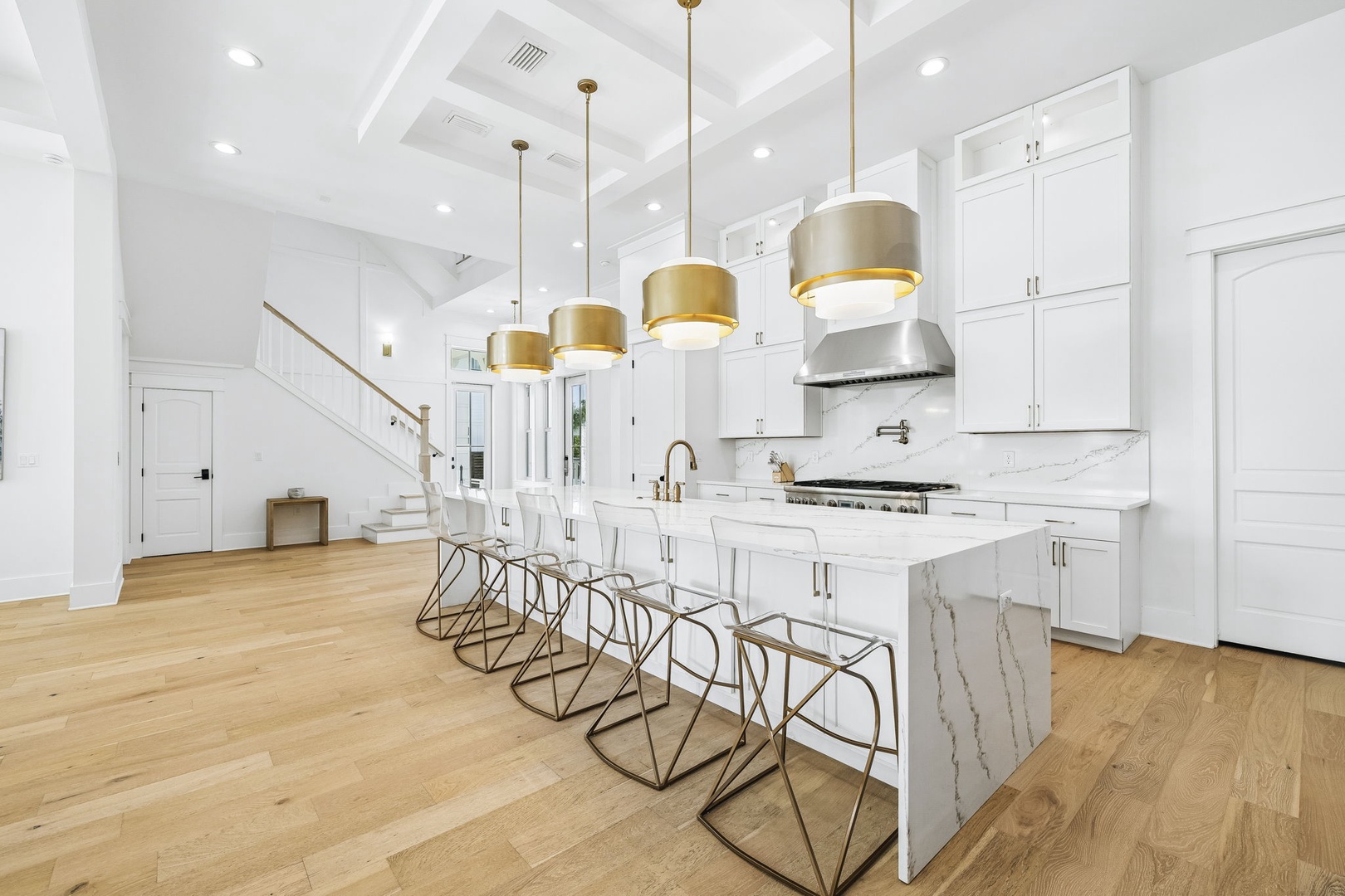 This bright, airy kitchen invites you to gather around the sleek marble island with friends, whether you're whipping up a gourmet meal or enjoying morning coffee under the warm glow of golden pendant lights.