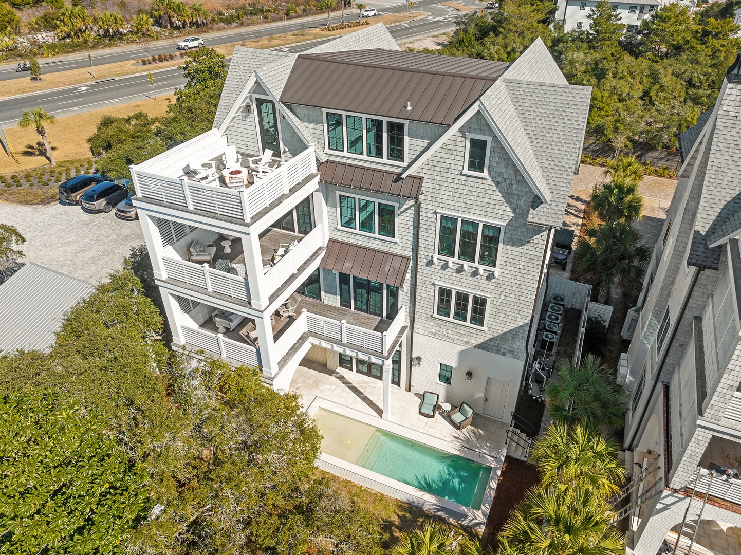 Modern coastal property featuring a private pool and multi-level balconies surrounded by lush landscaping and nearby beach access.