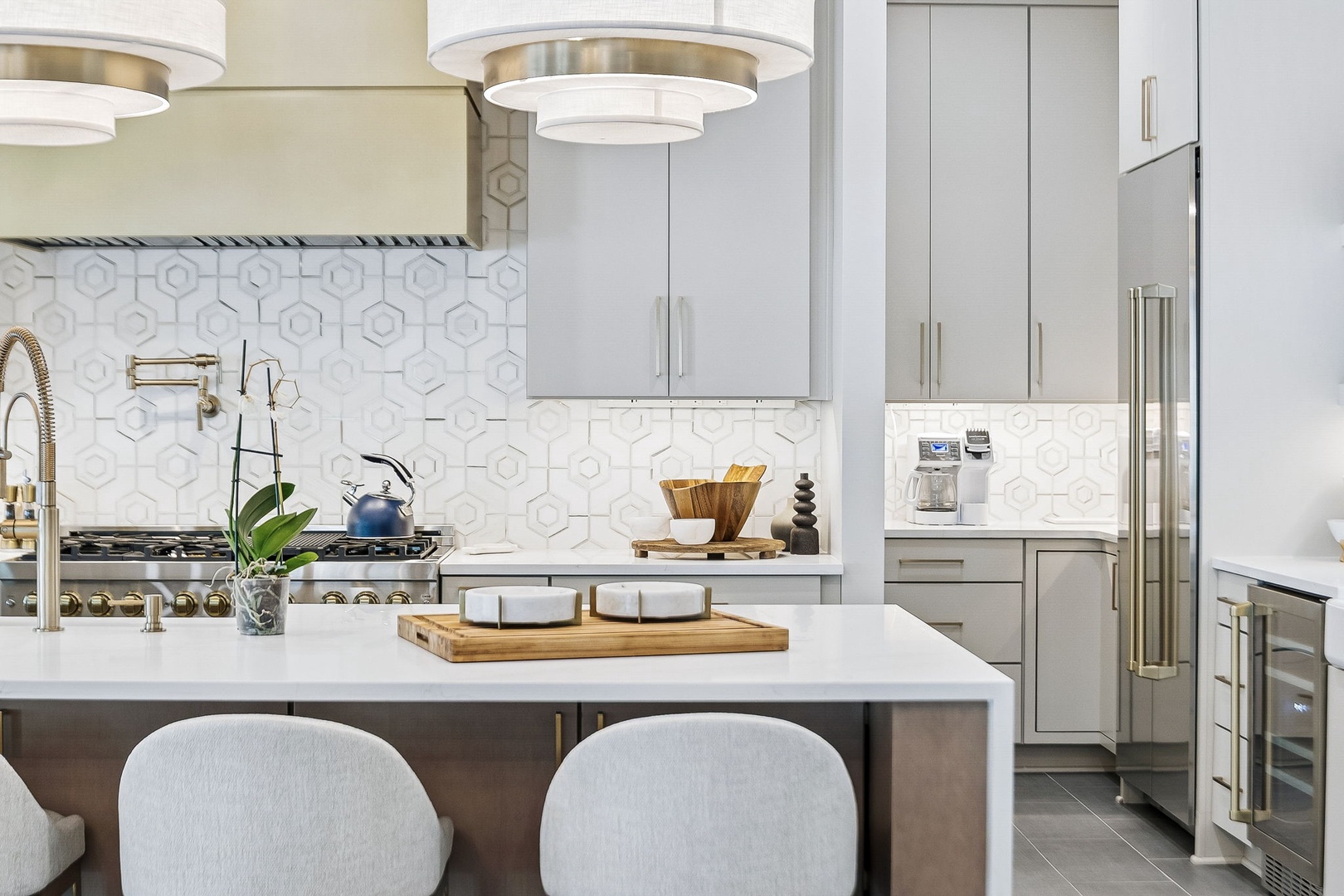 Picture yourself preparing meals in this stylish, modern kitchen. Elegant pendant lights illuminate gleaming countertops, while sleek cabinetry and top-of-the-line appliances make cooking a pleasure.