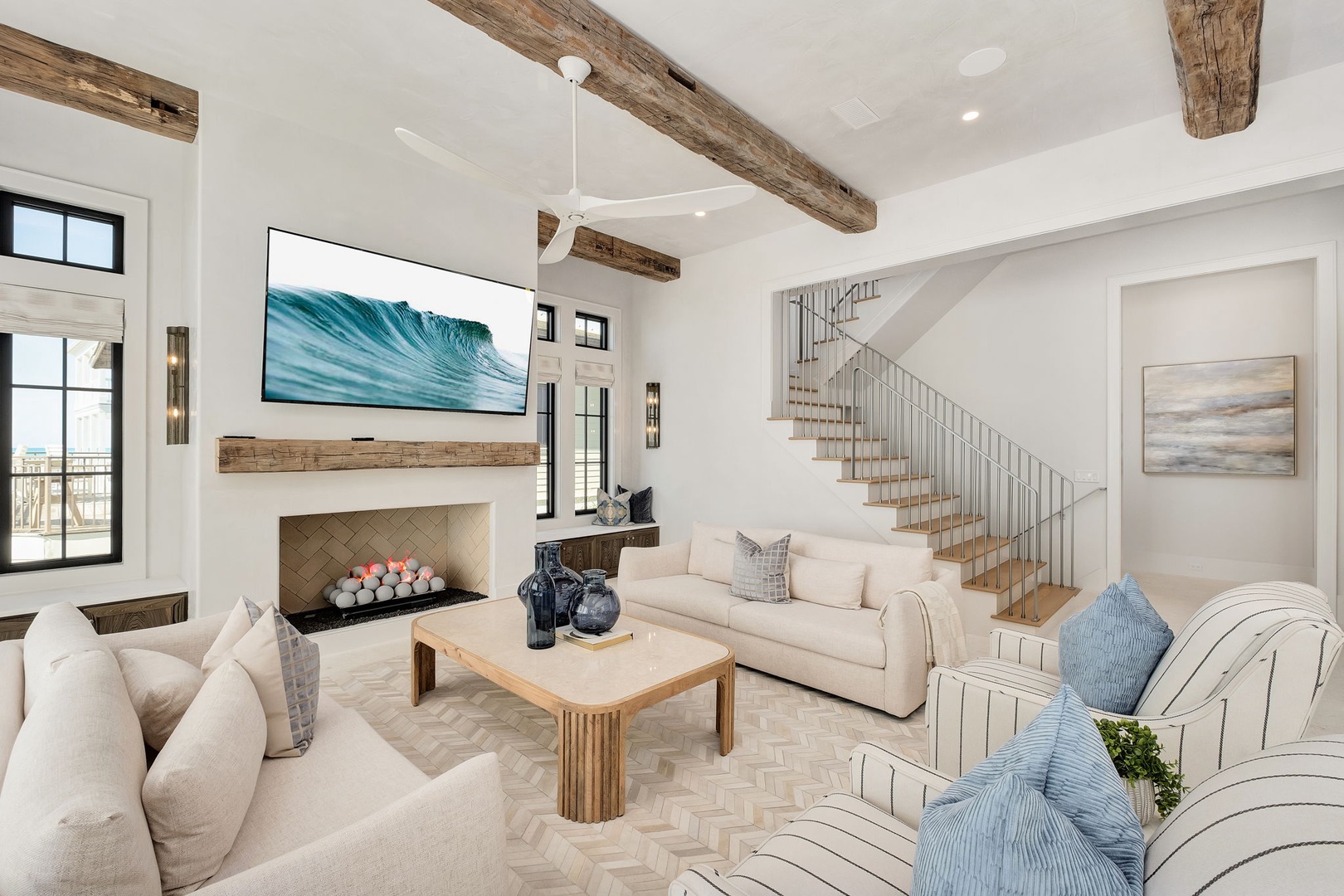 Unwind in your elegant living room where rustic beams meet modern luxury, complete with a cozy fireplace and coastal-inspired decor.