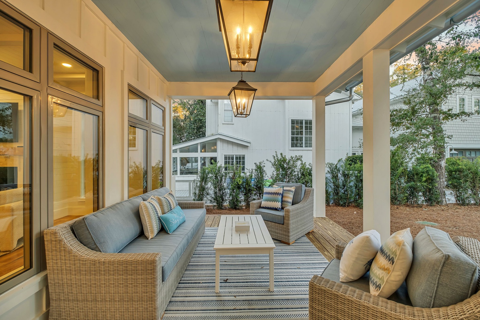 Unwind on your elegant covered porch with plush wicker seating, perfect for evening conversations under the soft lantern glow.