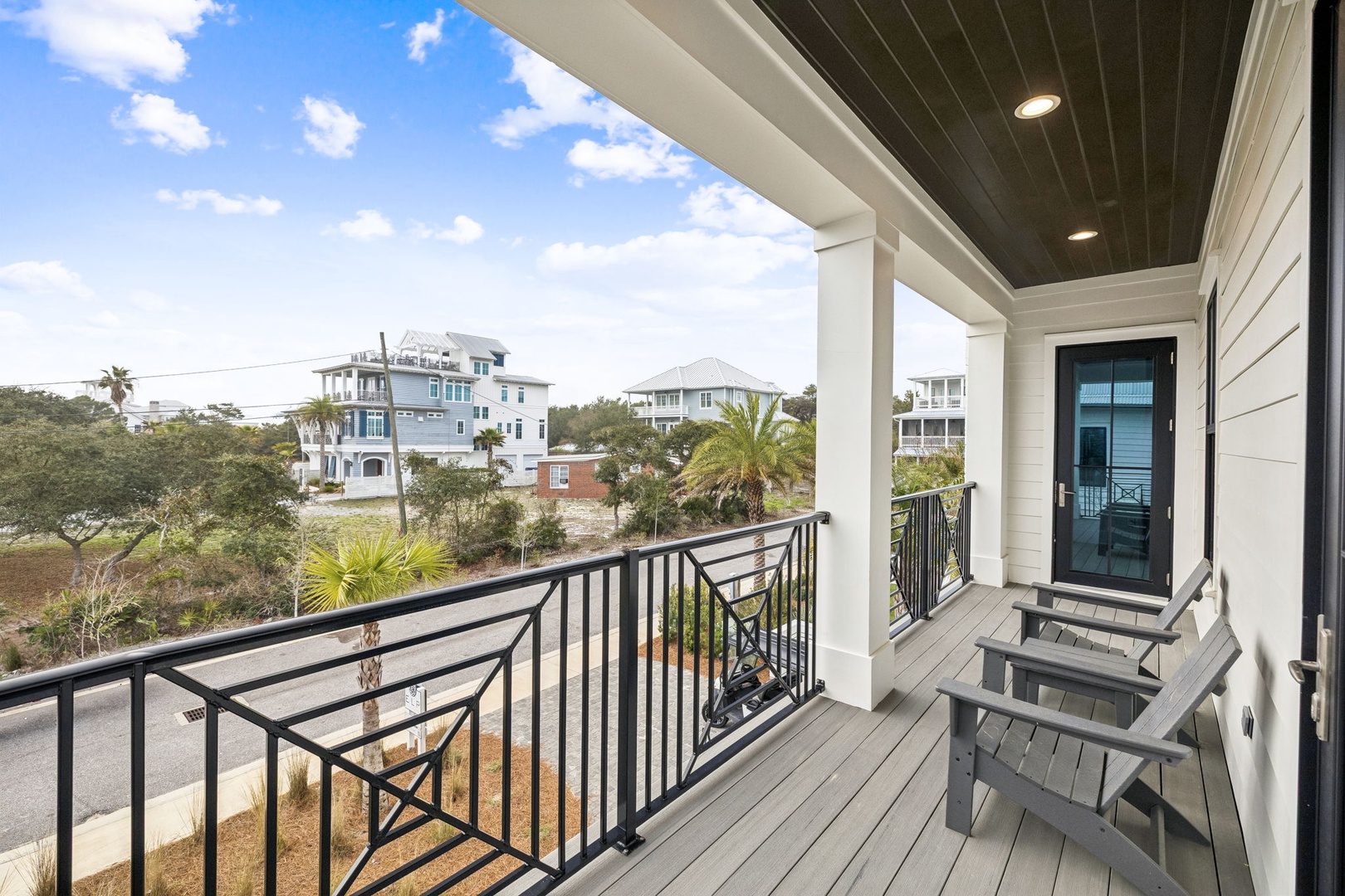 Unwind on your private balcony with comfortable seating and peaceful neighborhood views stretching toward tropical palms and coastal homes.