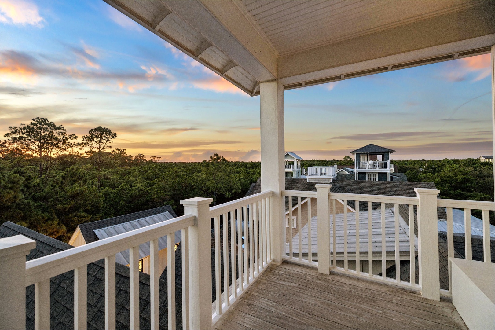 Sip your morning coffee on this private balcony as the sky lights up in soft pastels, with views sweeping over lush greenery and neighboring coastal homes.