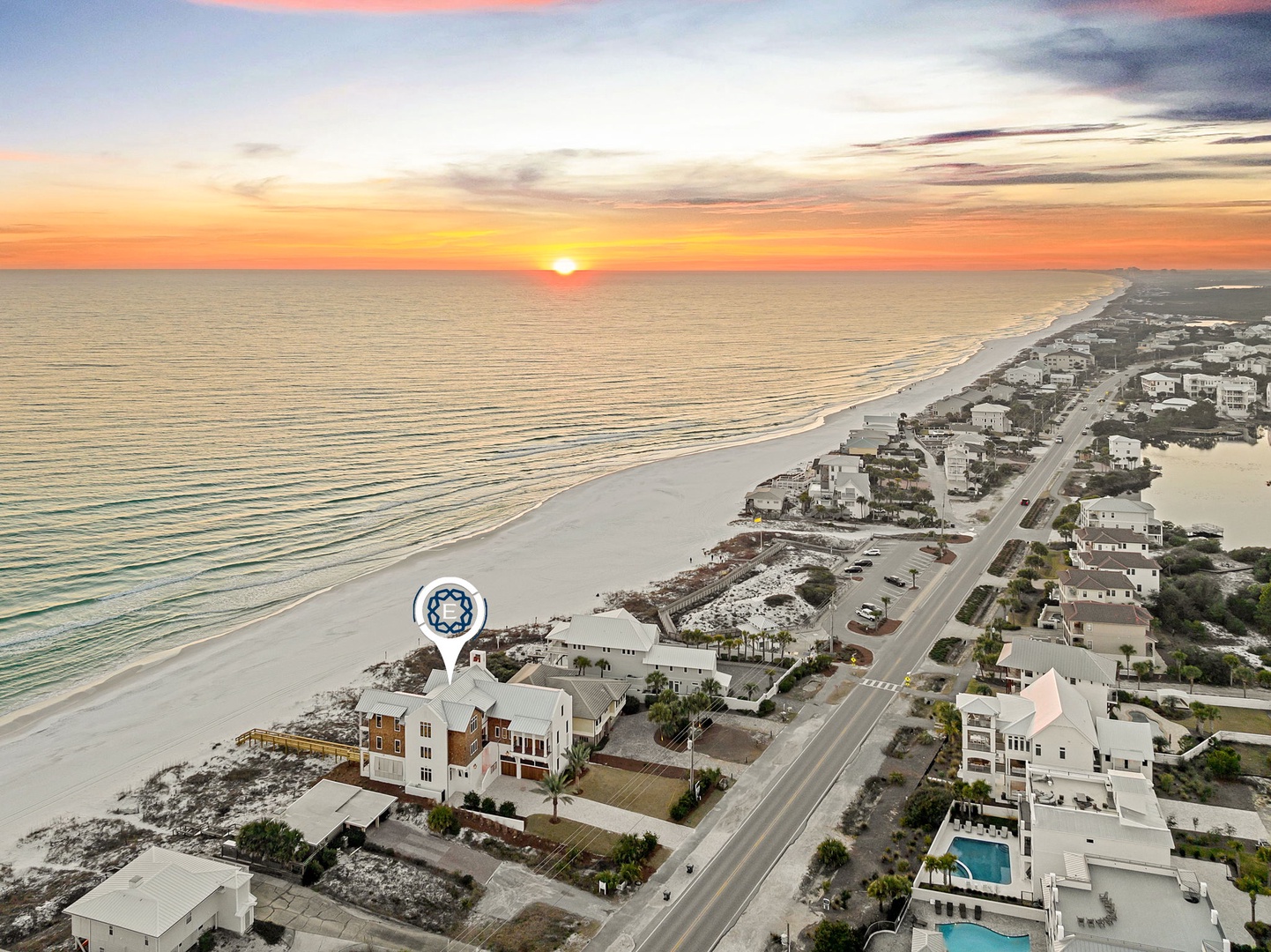 Stunning aerial view of beachfront community at sunset, showcasing pristine white sand beaches and coastal development along the shoreline.