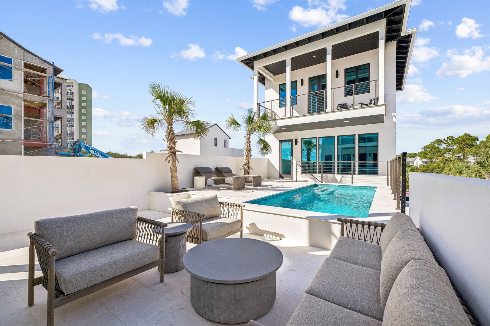 Modern coastal architecture frames your private pool oasis, with swaying palms and a spacious terrace where you can lounge, entertain, and enjoy effortless indoor-outdoor living.