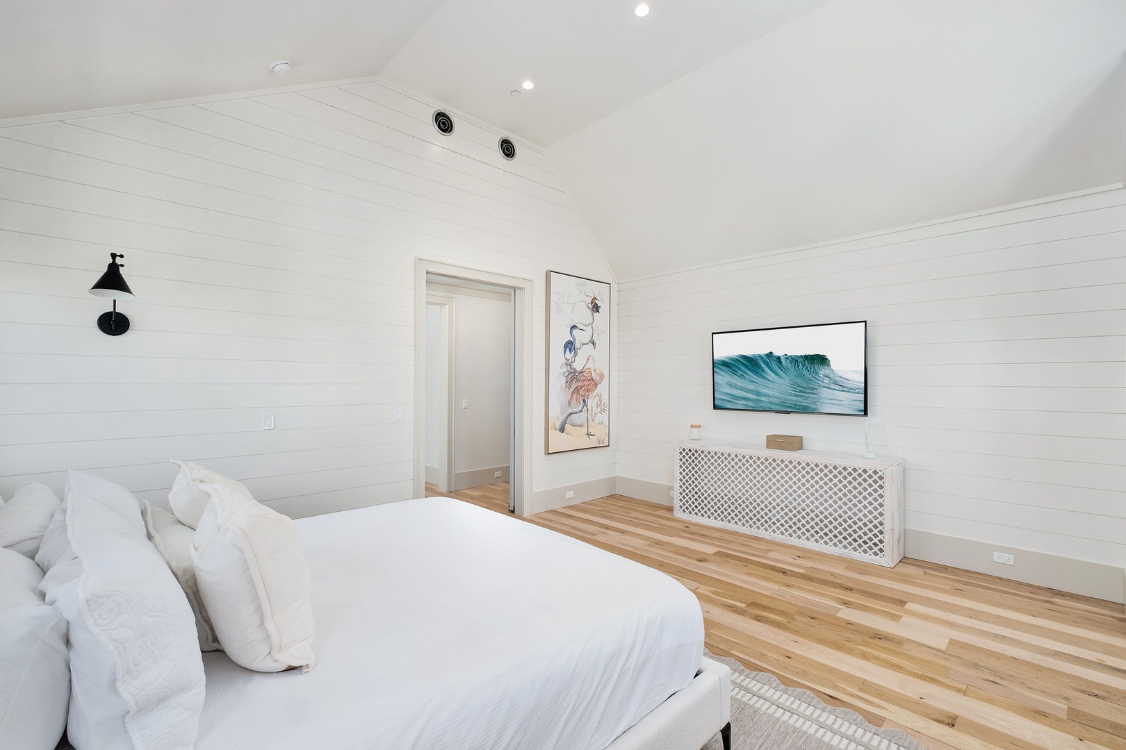 Drift off in your serene coastal bedroom where crisp white linens and warm wood floors create the perfect retreat.