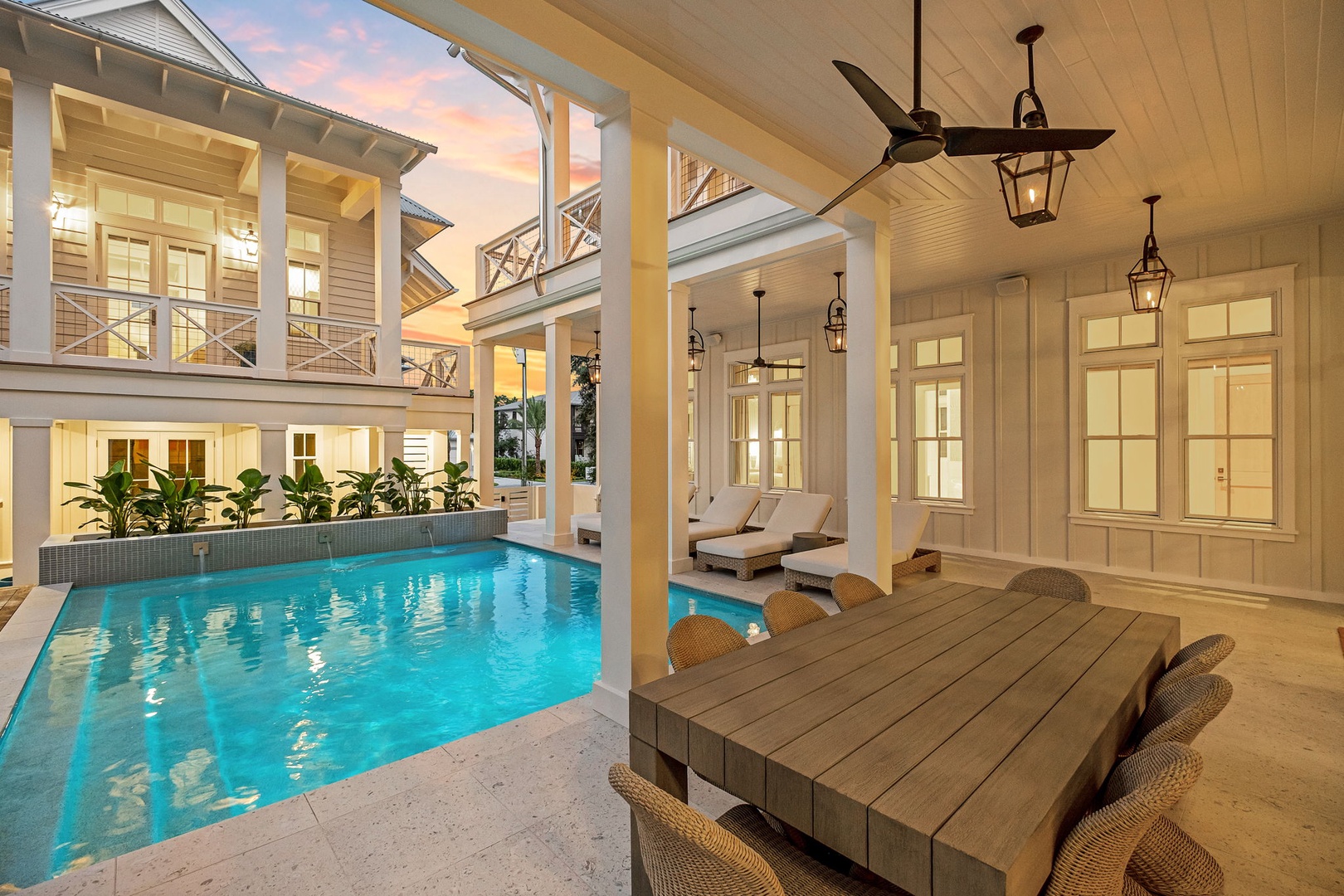 Step into your private oasis where a sparkling pool awaits beneath elegant lanterns and a ceiling fan. Wicker seating and loungers invite you to unwind in style, while soft evening light filters through the open courtyard design.