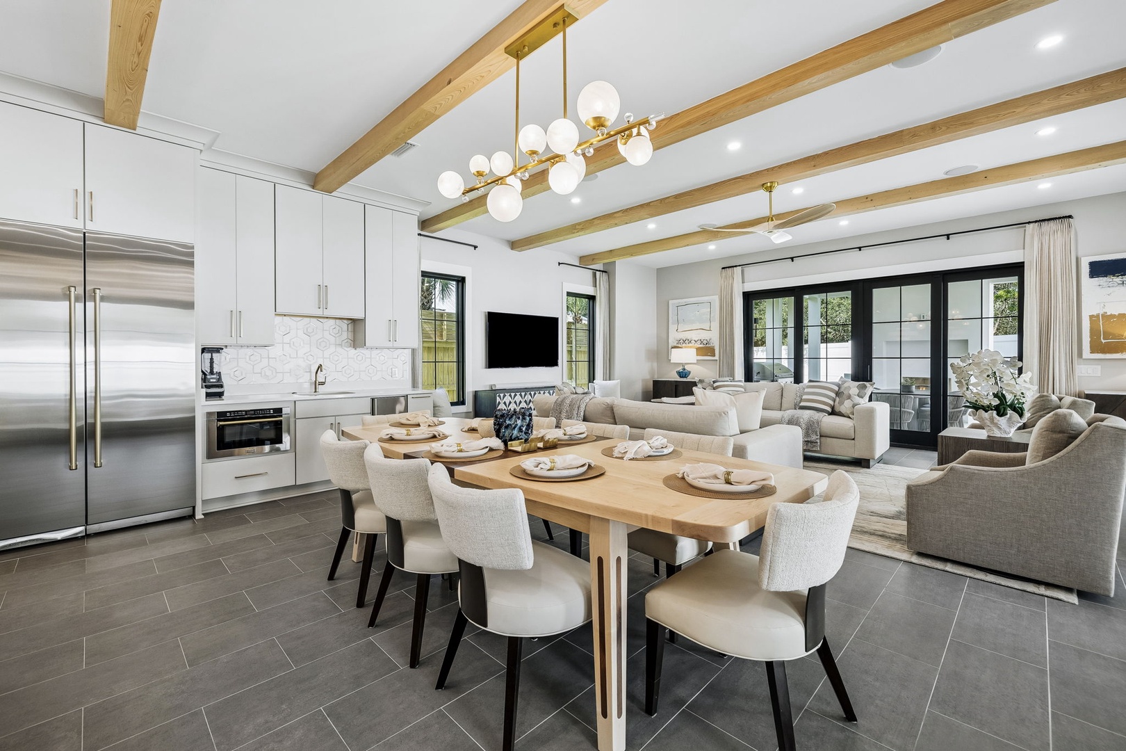 Relax in your beautifully designed open-concept space, where natural wood beams frame soaring ceilings above modern dining and living areas. You'll love gathering around the handcrafted table or unwinding on plush sofas.