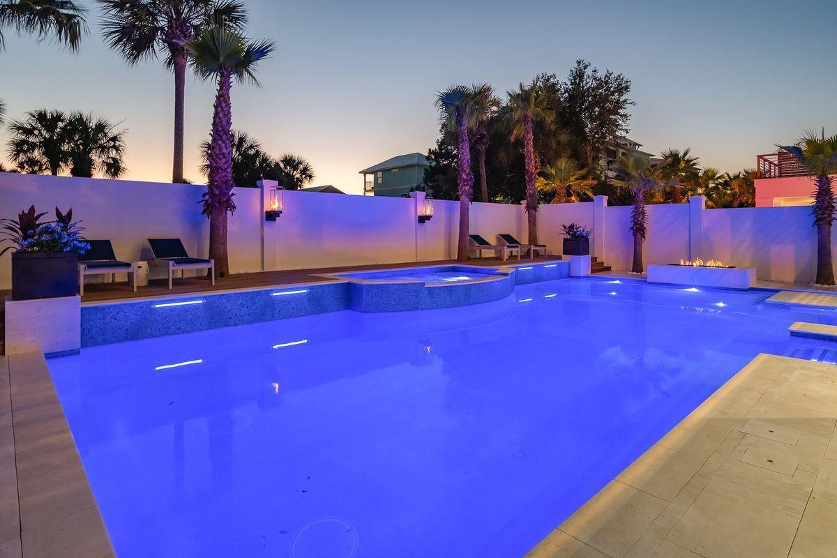 Stunning illuminated pool with tropical palms creates the perfect evening atmosphere for relaxation and entertainment.