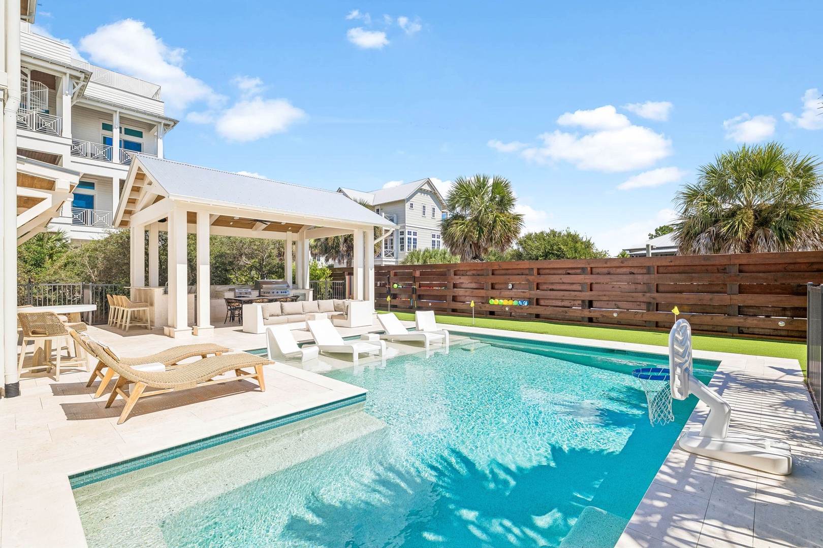 This inviting pool beckons you to unwind under warm coastal sunshine. With built-in ledge seating and a shaded pavilion just steps away, your days are made for barefoot lounging and leisurely swims.