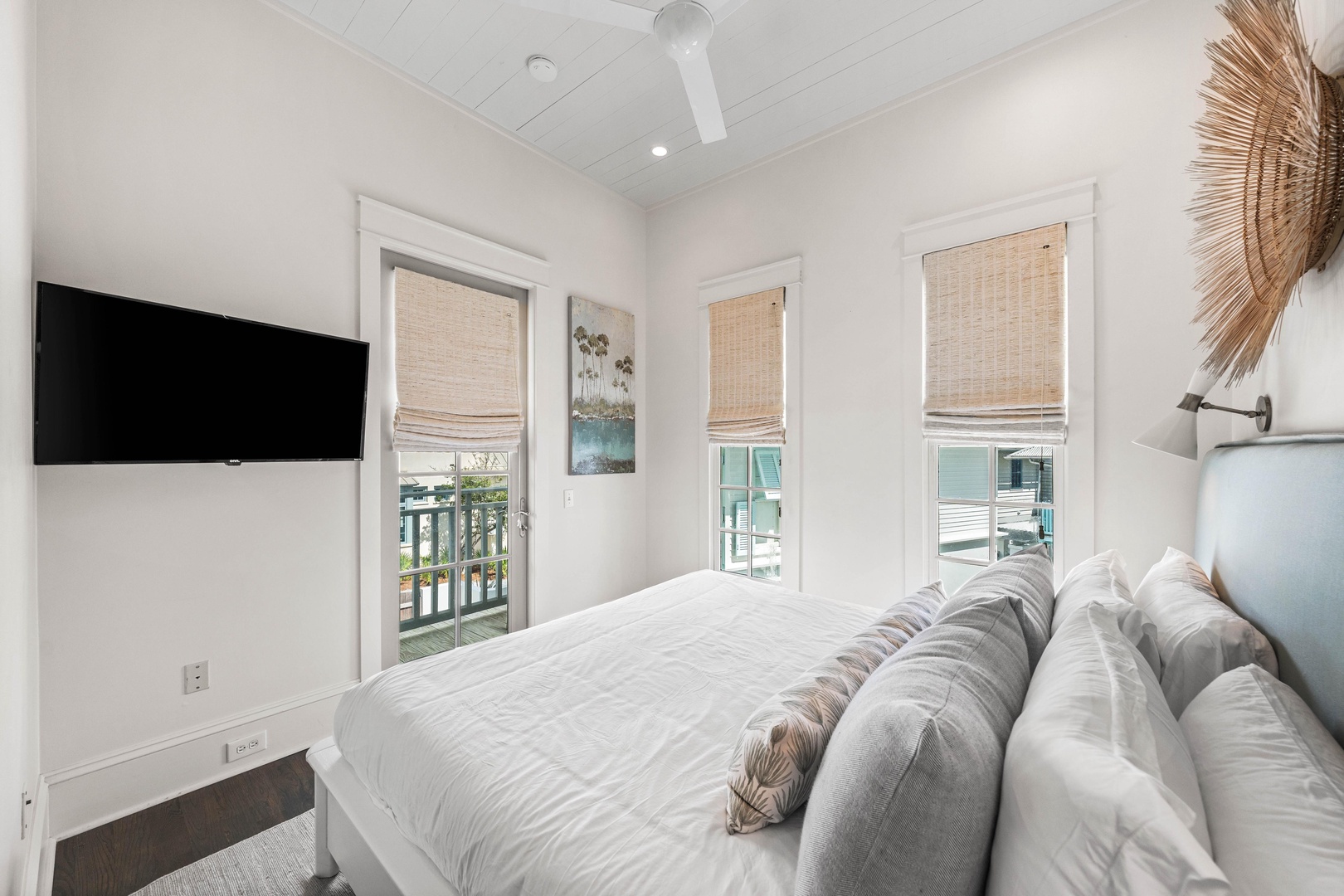 Wake up to natural light filtering through woven shades in your serene bedroom retreat with ceiling fan comfort and modern TV entertainment.