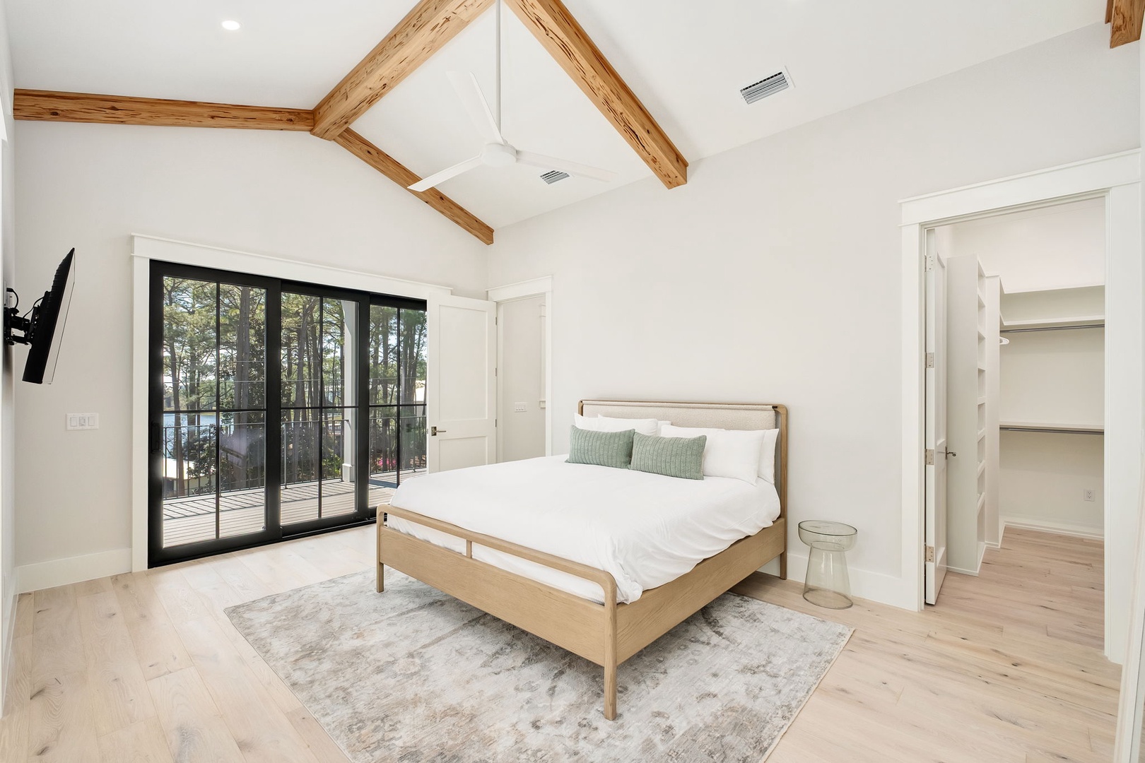 Your serene bedroom features exposed wood beams, crisp white linens, and sliding doors opening to a private outdoor space.