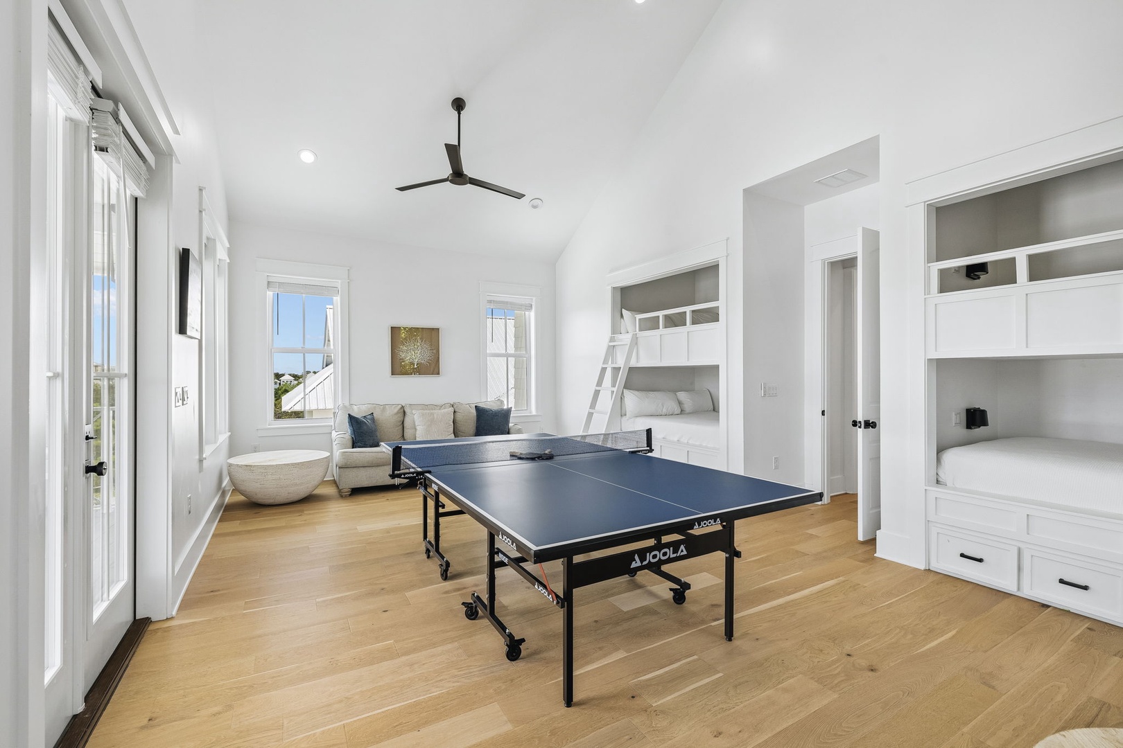 Your game room awaits with built-in bunk nooks and a ping-pong table for friendly competitions. Natural light pours through tall windows, creating an inviting space for relaxation and play.