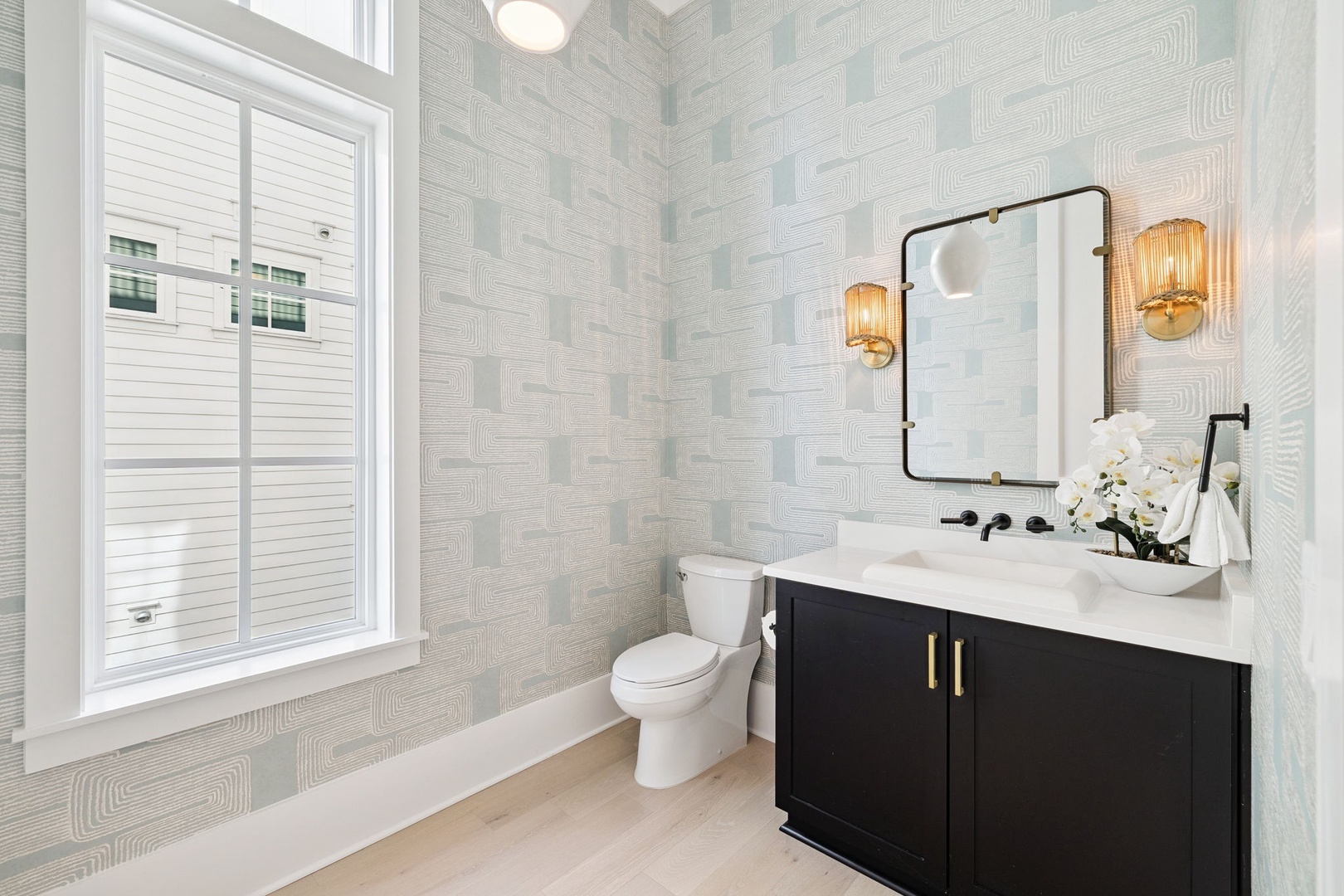 Step into your private powder room featuring elegant geometric wallpaper, warm brass fixtures, and a sleek vanity that creates the perfect morning routine.