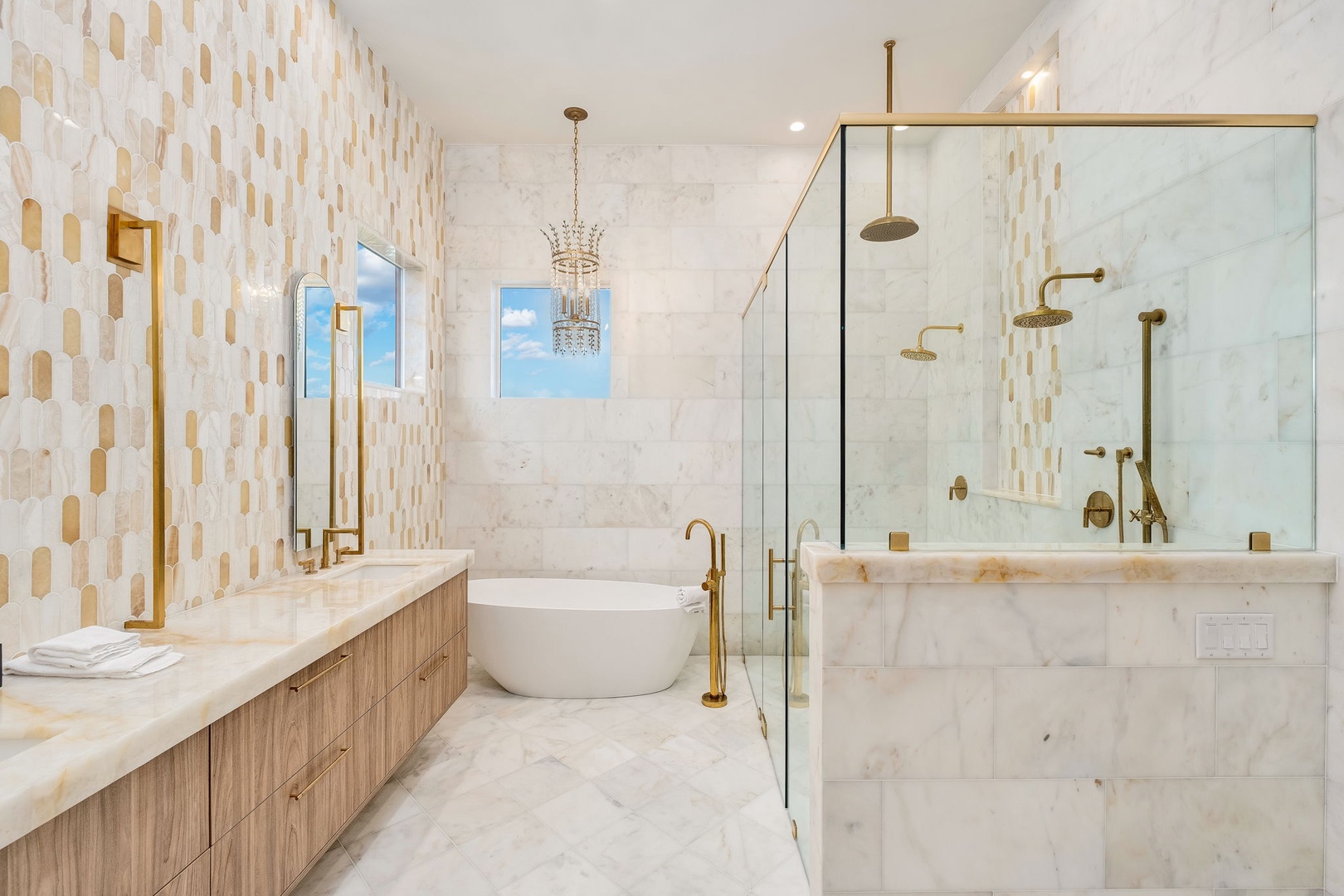 Indulge in this elegant marble bathroom featuring a luxurious soaking tub, spacious walk-in shower with brass fixtures, and beautiful honeycomb accent tiles that create a warm, sophisticated retreat.