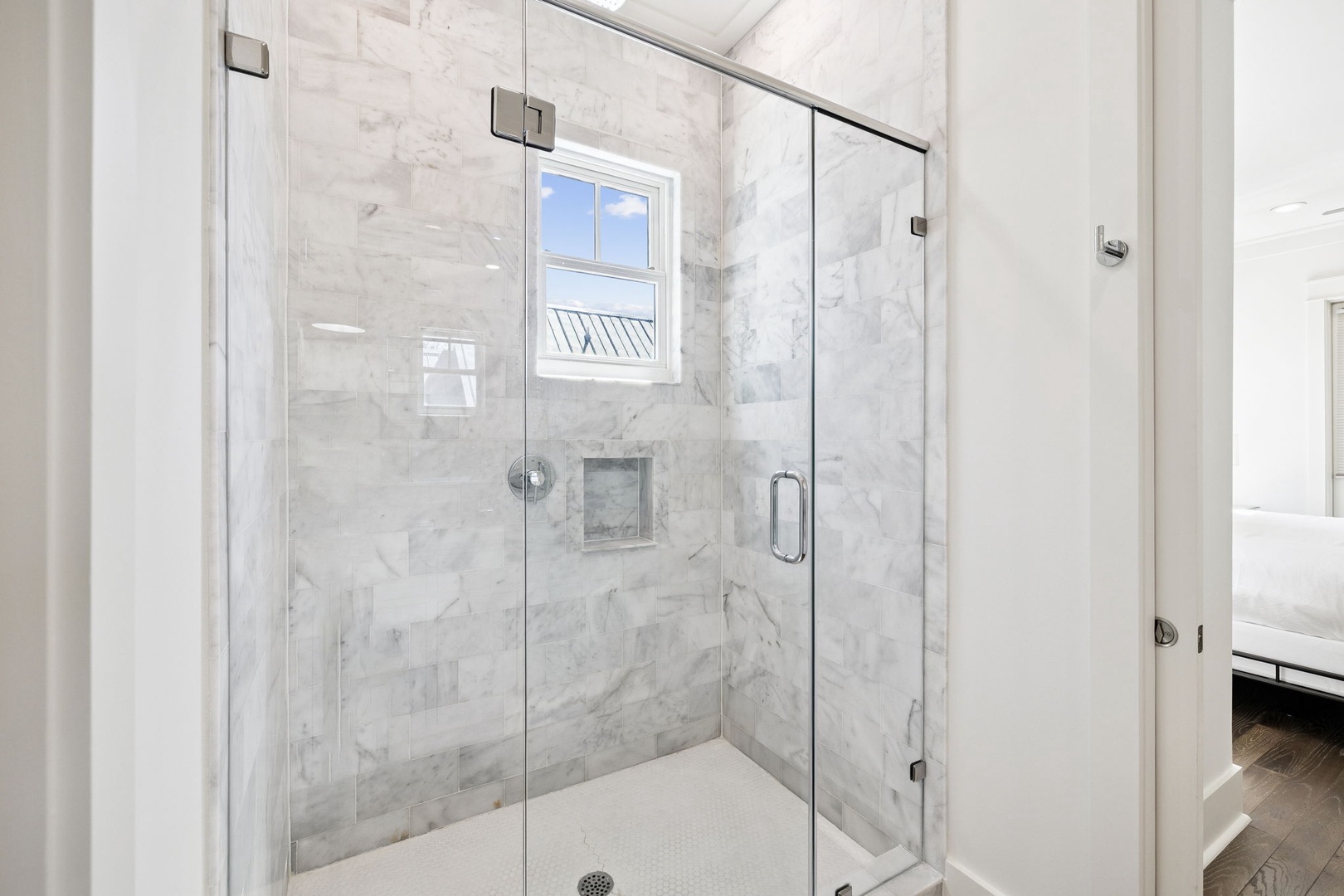 Step into your private marble oasis with luxurious glass-enclosed shower featuring natural light and premium finishes.