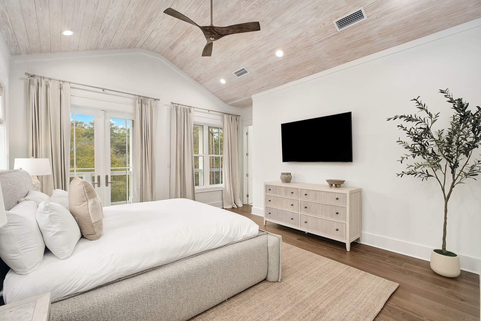 Drift off beneath your private wood-planked ceiling where natural light fills your serene bedroom retreat through elegant French doors.