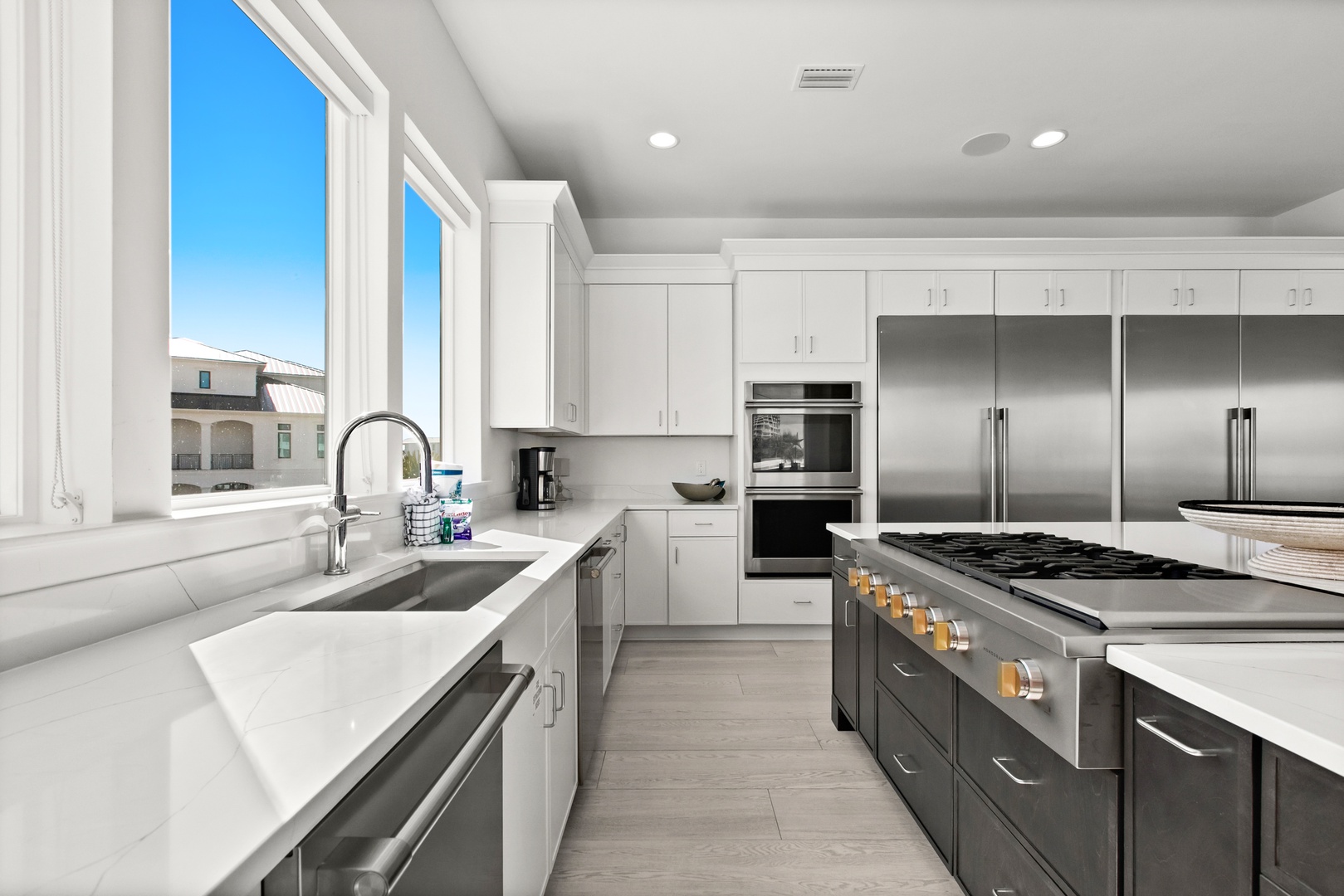 Picture yourself cooking in this spacious chef's kitchen with gleaming stainless appliances, pristine white cabinetry, and abundant natural light streaming through tall windows.