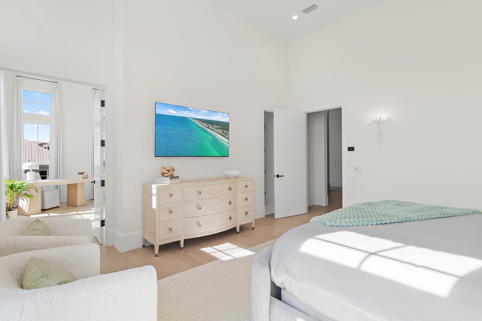 Relax in your bright, spacious bedroom with coastal charm, plush seating, and a stunning sea view on the screen to inspire your getaway.