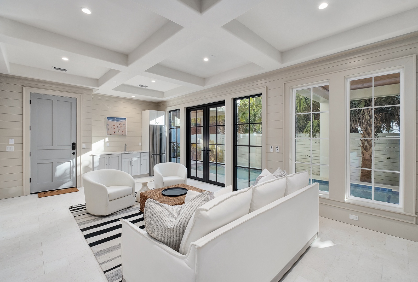Sink into plush white seating while natural light streams through floor-to-ceiling windows, revealing your private pool just steps away.