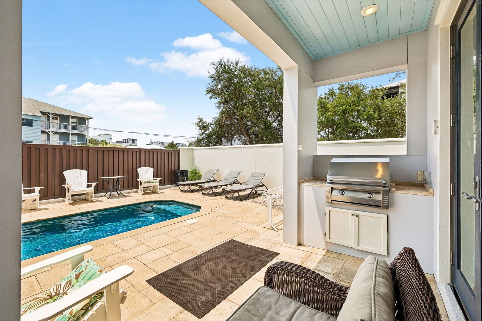 This covered outdoor area invites you to unwind by your private pool, grill up a meal at the built-in BBQ station, and lounge on sun chairs under blue skies and swaying trees.