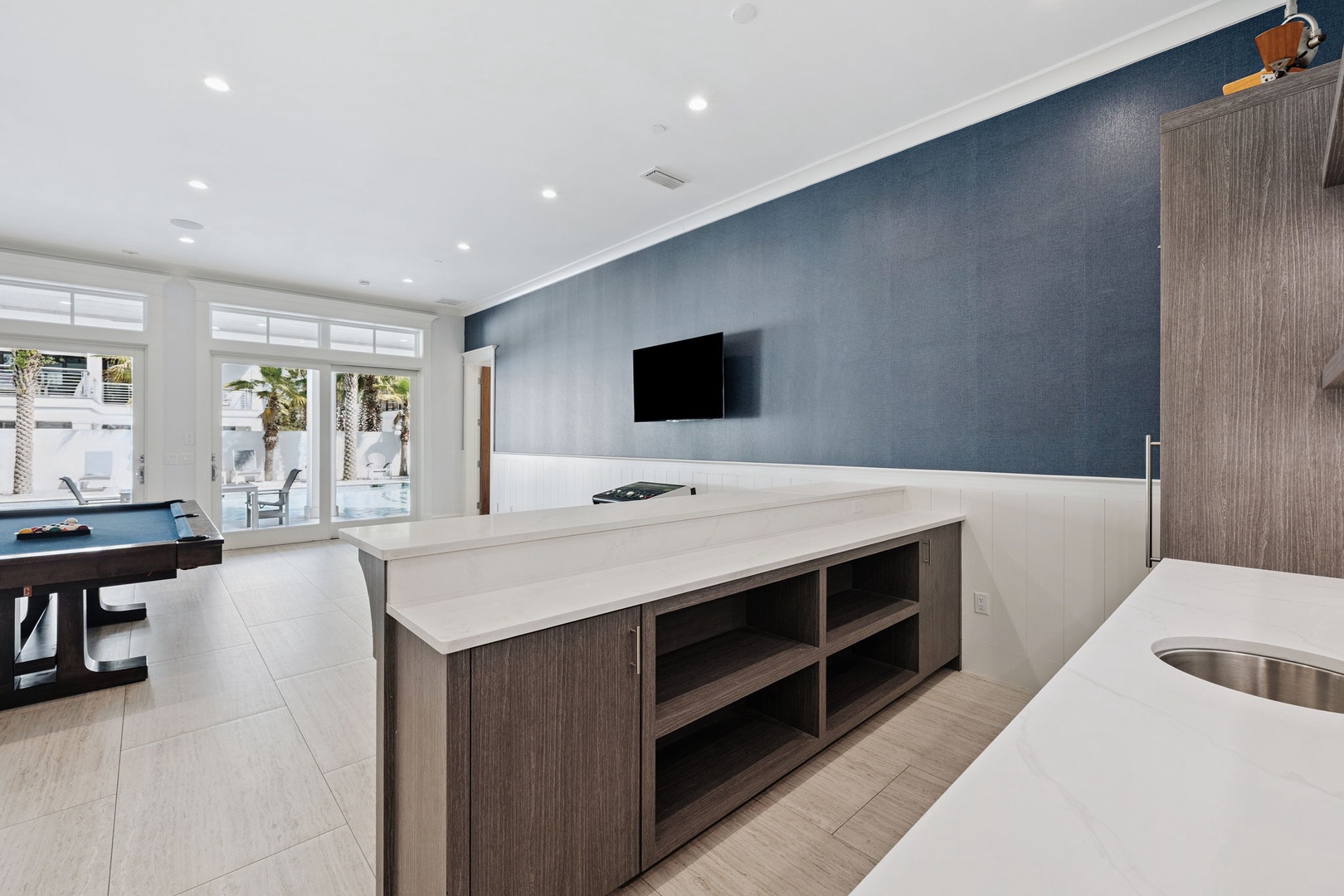 Your modern kitchen flows seamlessly into the entertainment area, where sleek countertops meet cozy game nights and poolside views.