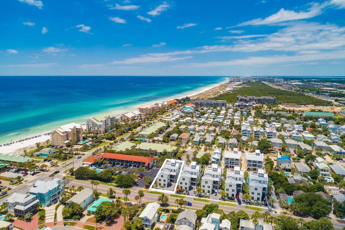 Stunning aerial view of beachfront vacation rentals along pristine white sand beaches and turquoise waters in this coastal paradise destination.